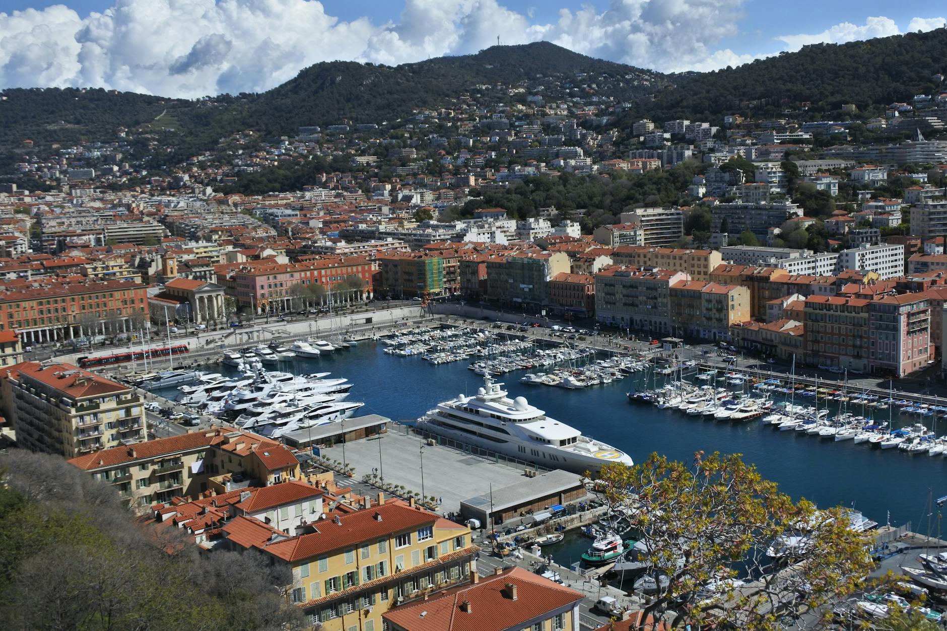 Aerial view of Nice harbor, yachts, city blocks, and surrounding hills