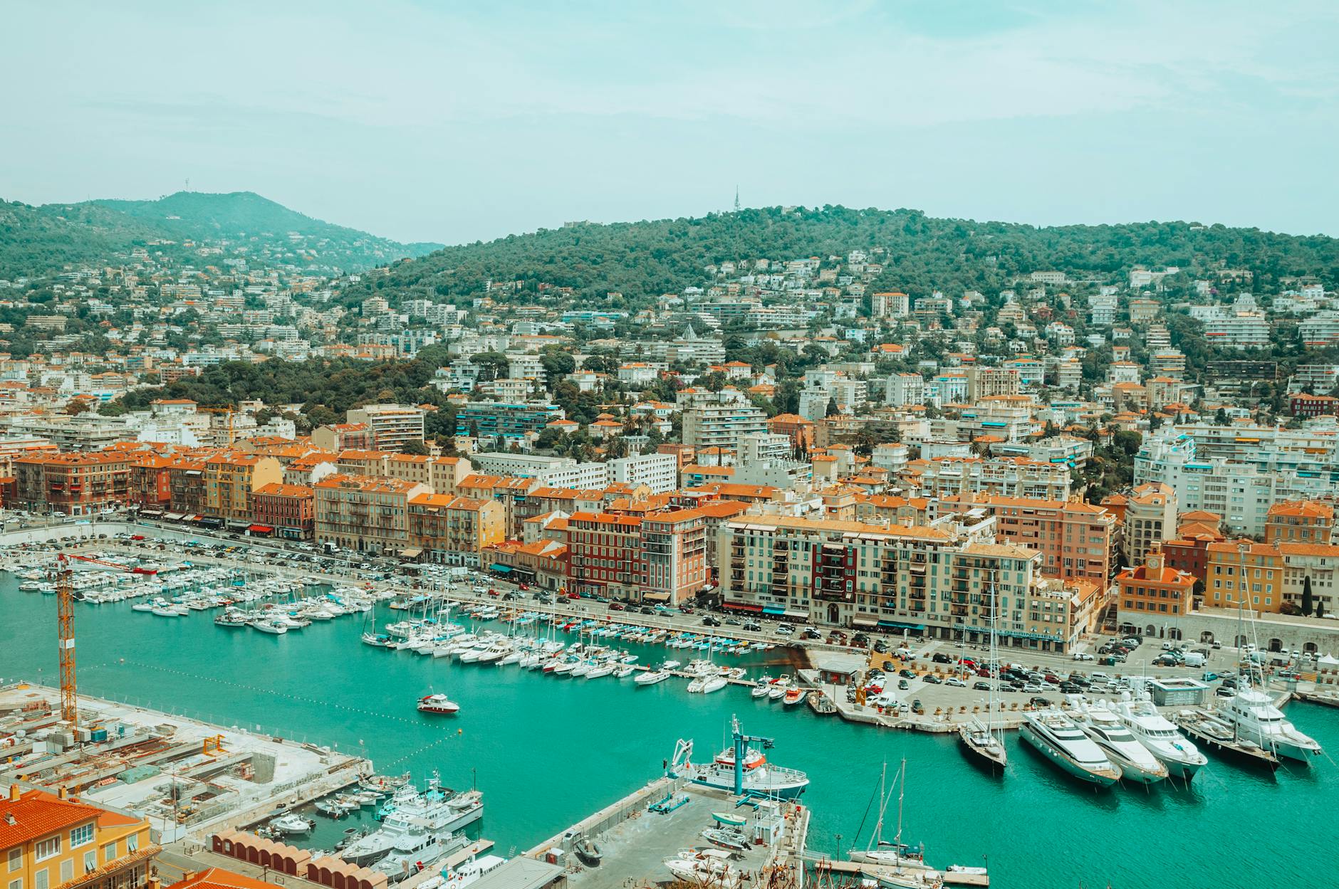 Aerial view of Nice Port, boats, urban buildings, and green hills
