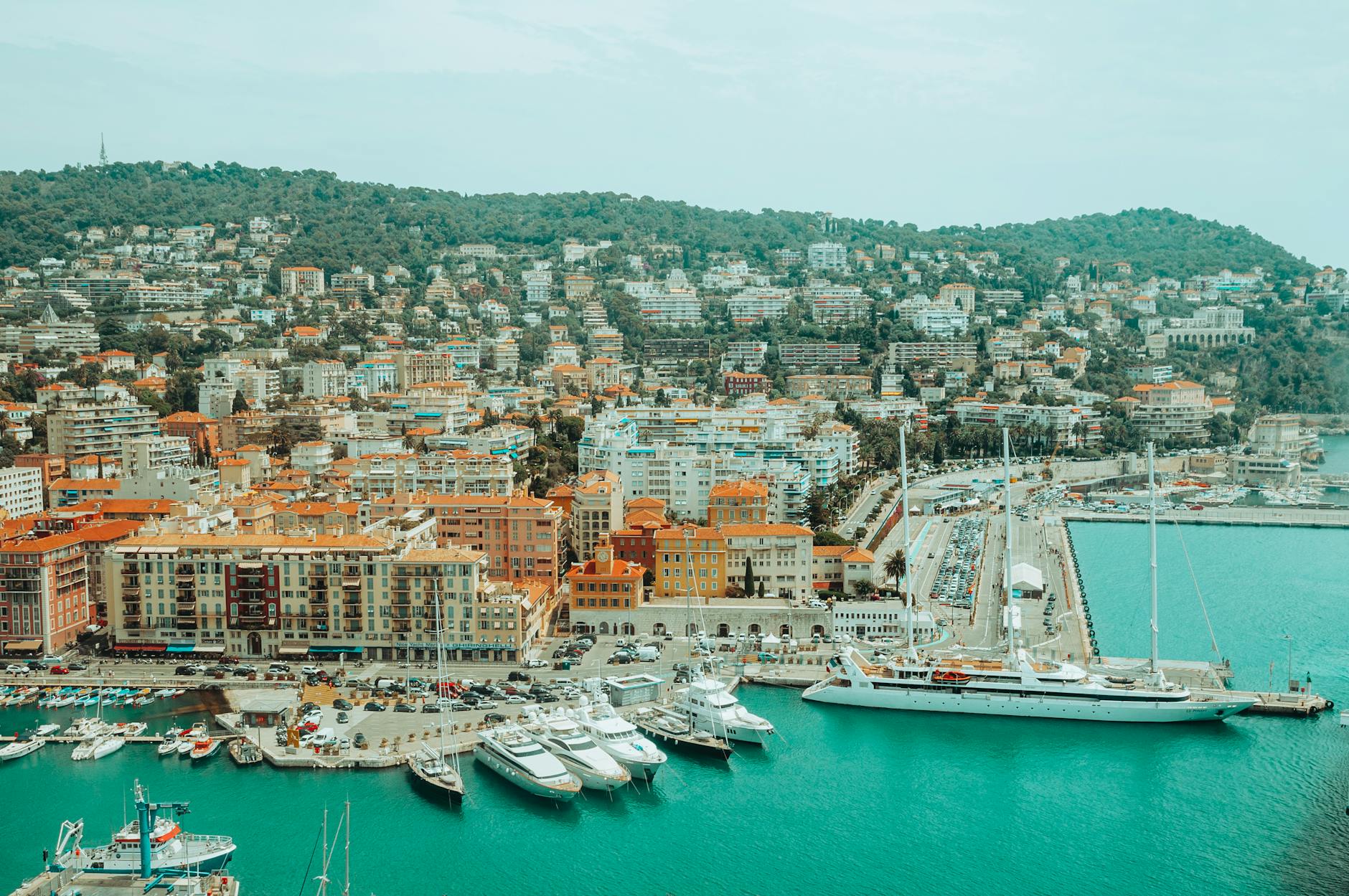 Aerial view of a Mediterranean harbor with yachts and hillside buildings