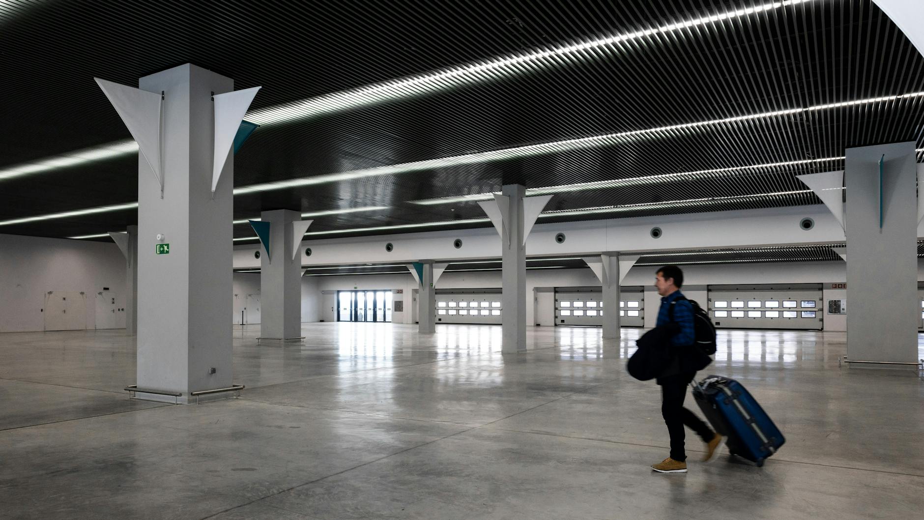Traveler with luggage walking through a modern airport hall
