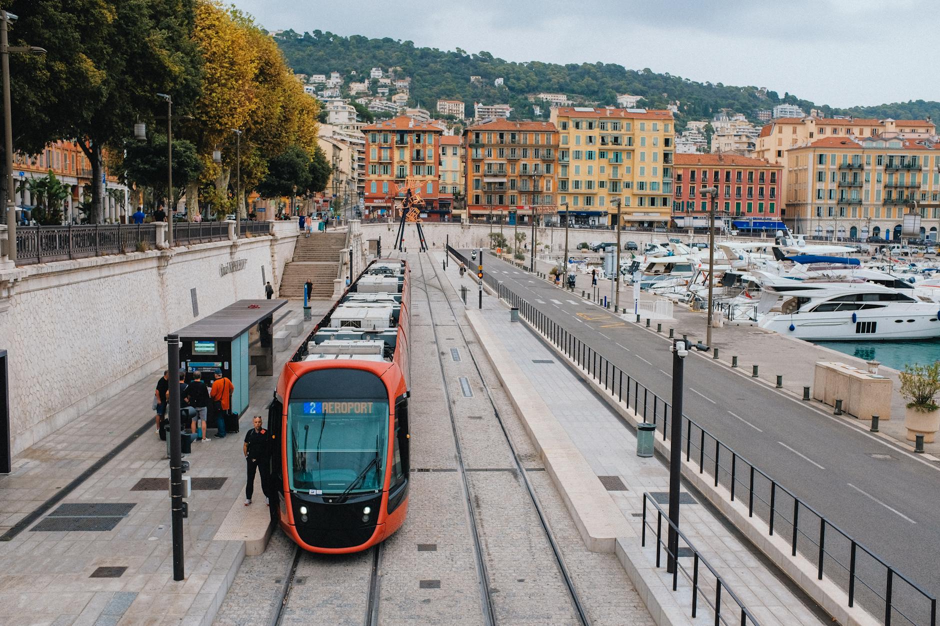 Red tram at a station near the Nice marina
