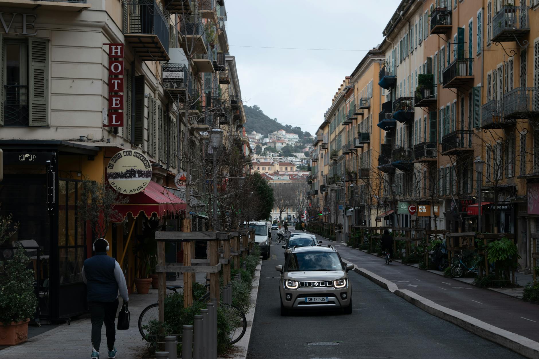 Quaint Nice street with buildings, cars, and pedestrians