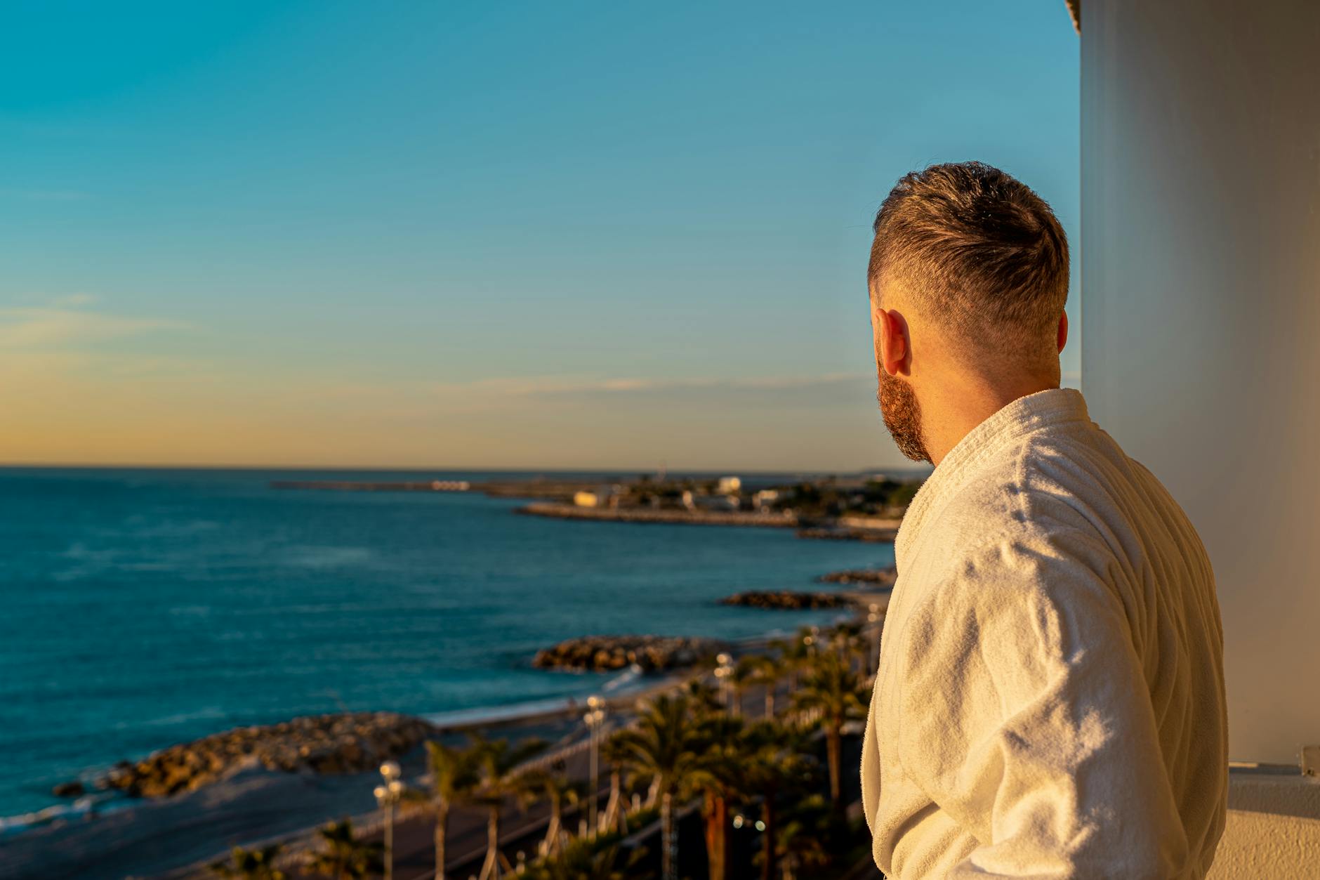 Traveler in a robe looking from a balcony toward the Nice coast