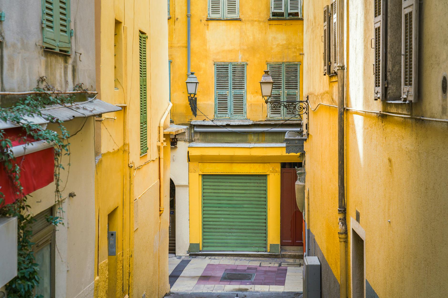 Narrow Nice alley with yellow buildings and shuttered windows