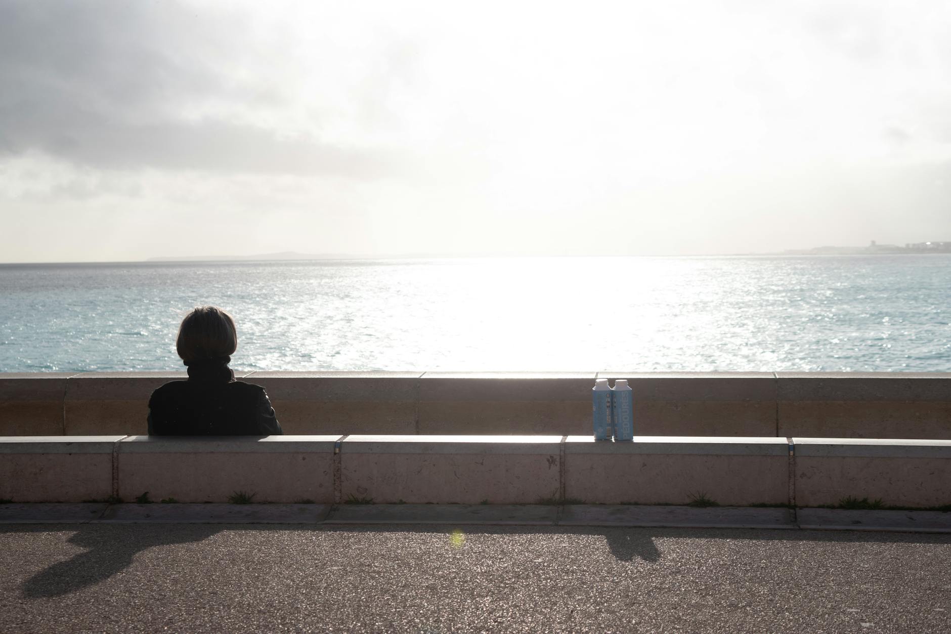 Person sitting on the promenade in Nice facing the sea
