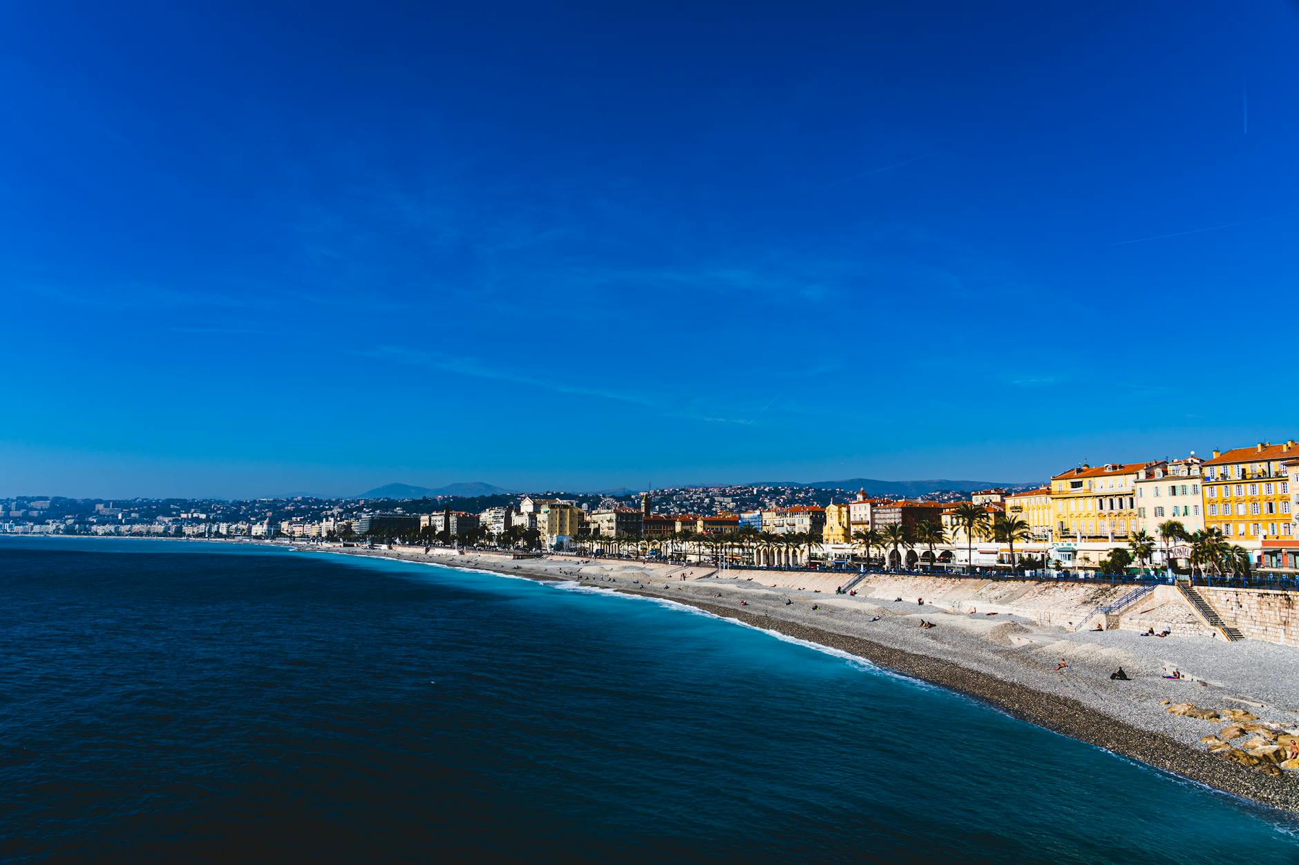 Beachfront view of Nice with blue water and colorful buildings