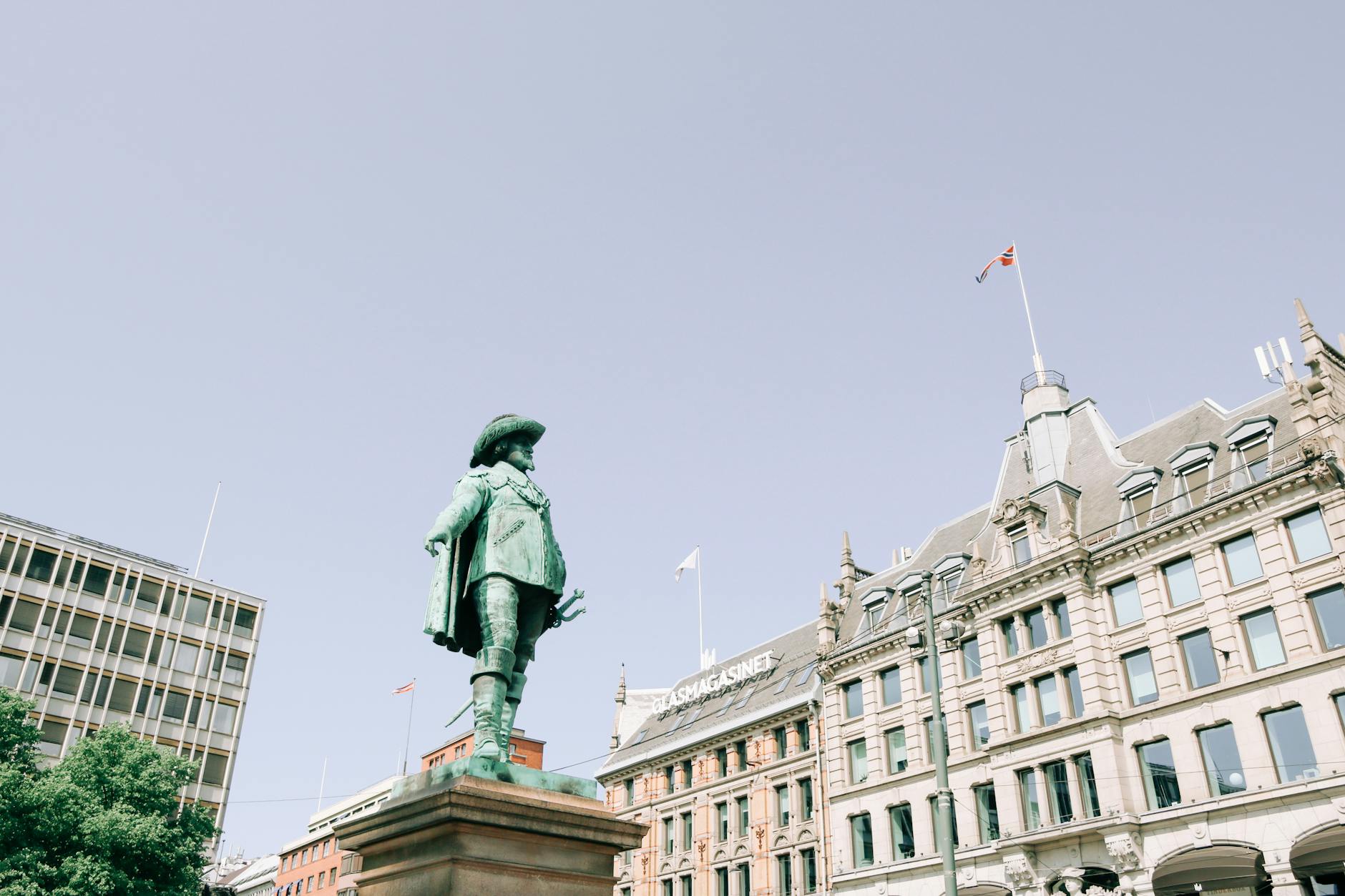 Statue of a Danish-Norwegian king in Oslo with city buildings