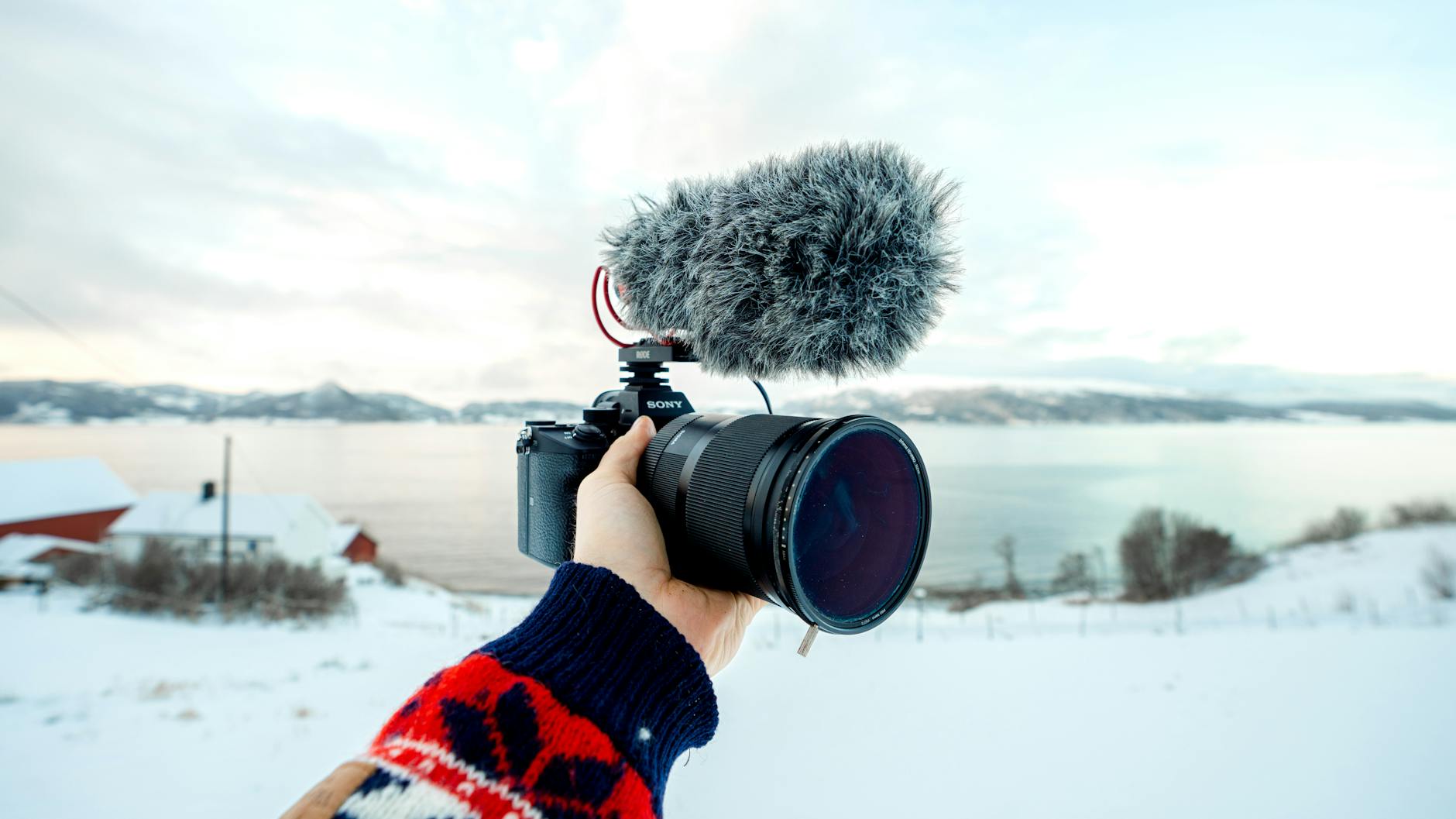 Camera with microphone held against a snowy Norwegian landscape