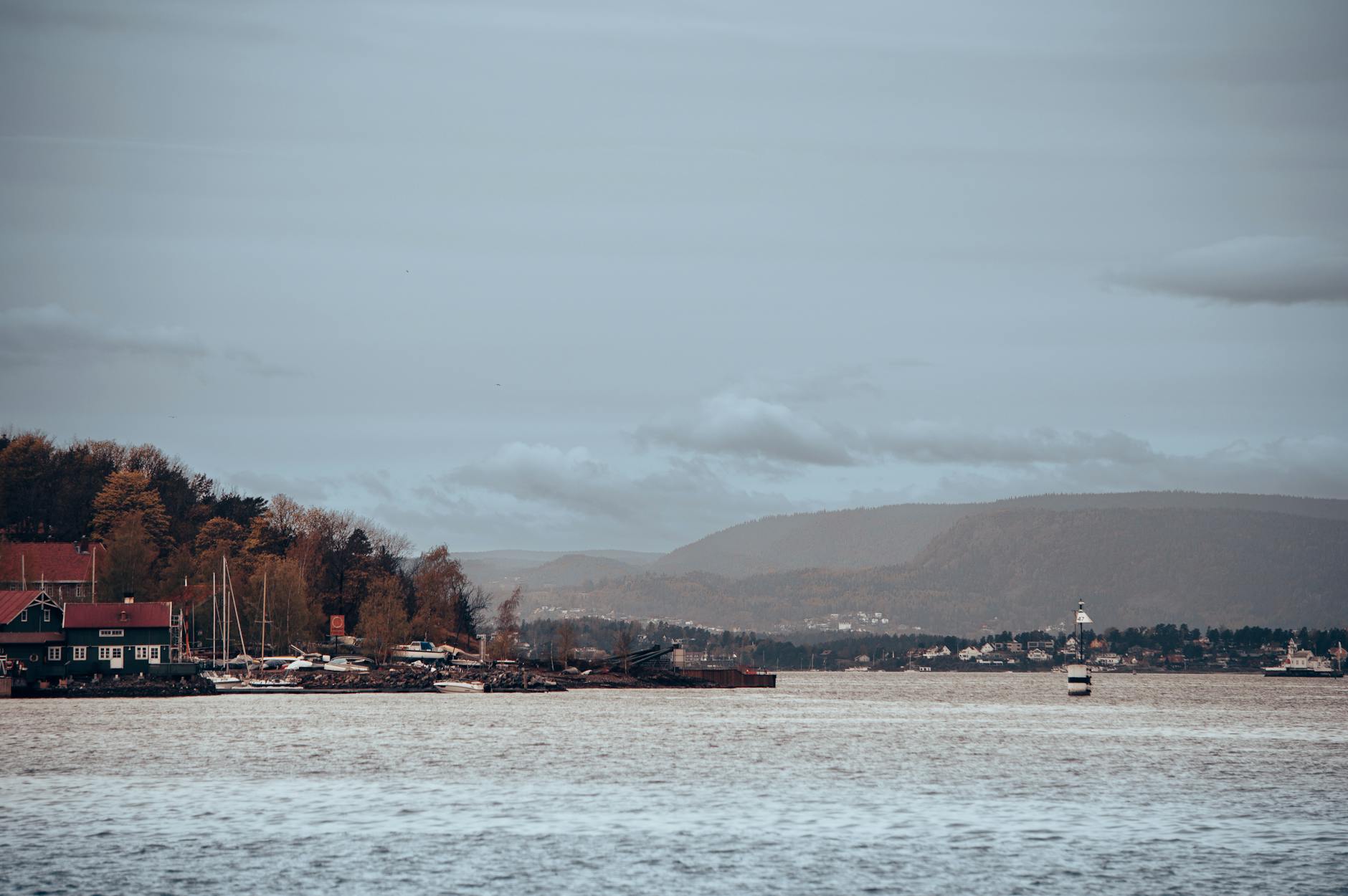 Oslo harbor view with watercraft and distant hills under a gray sky