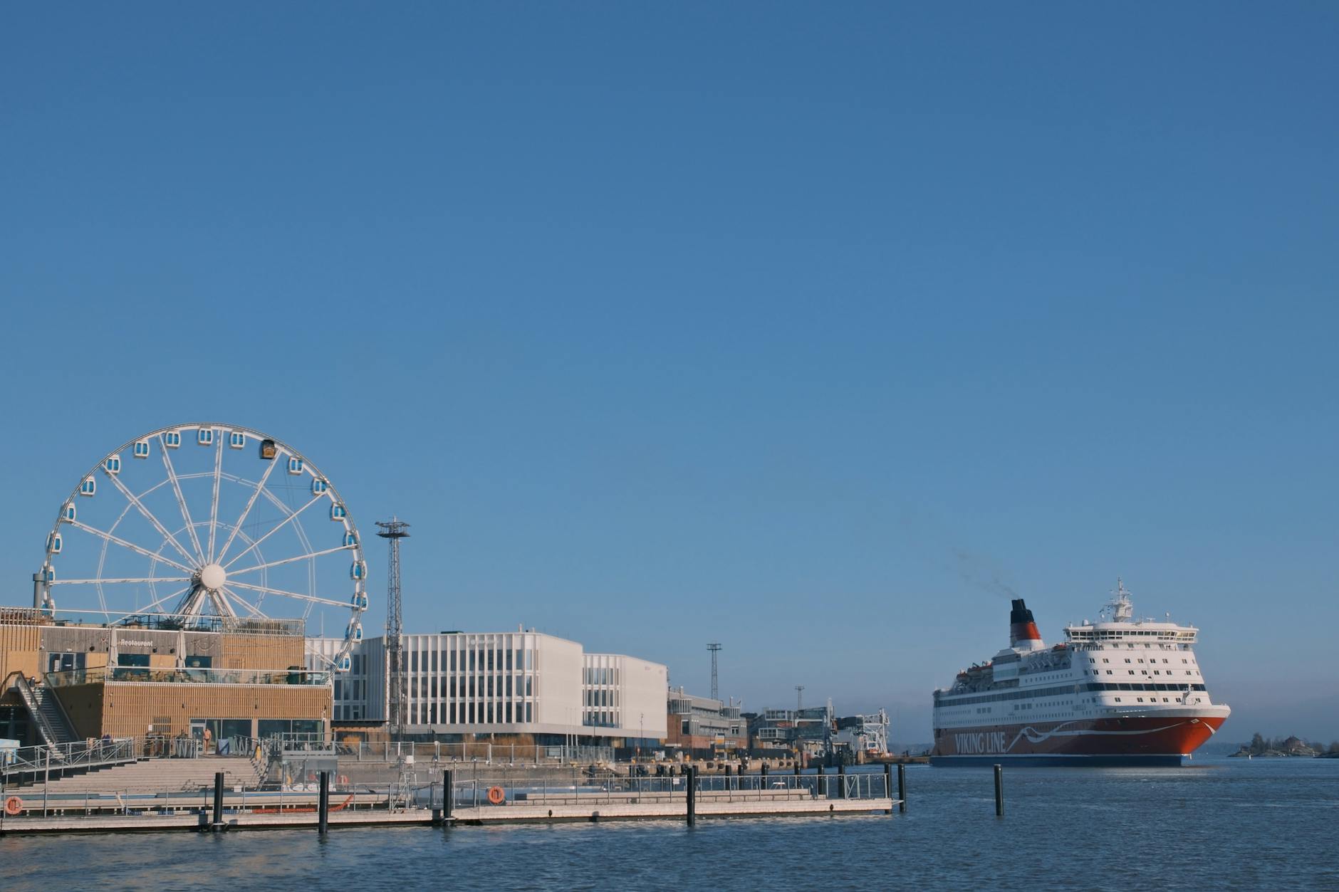 Cruise ship near a ferris wheel in a busy harbor