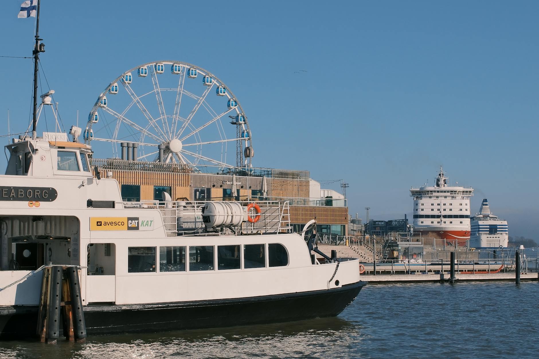 Oslo harbor scene with ferry, cruise ship, and ferris wheel