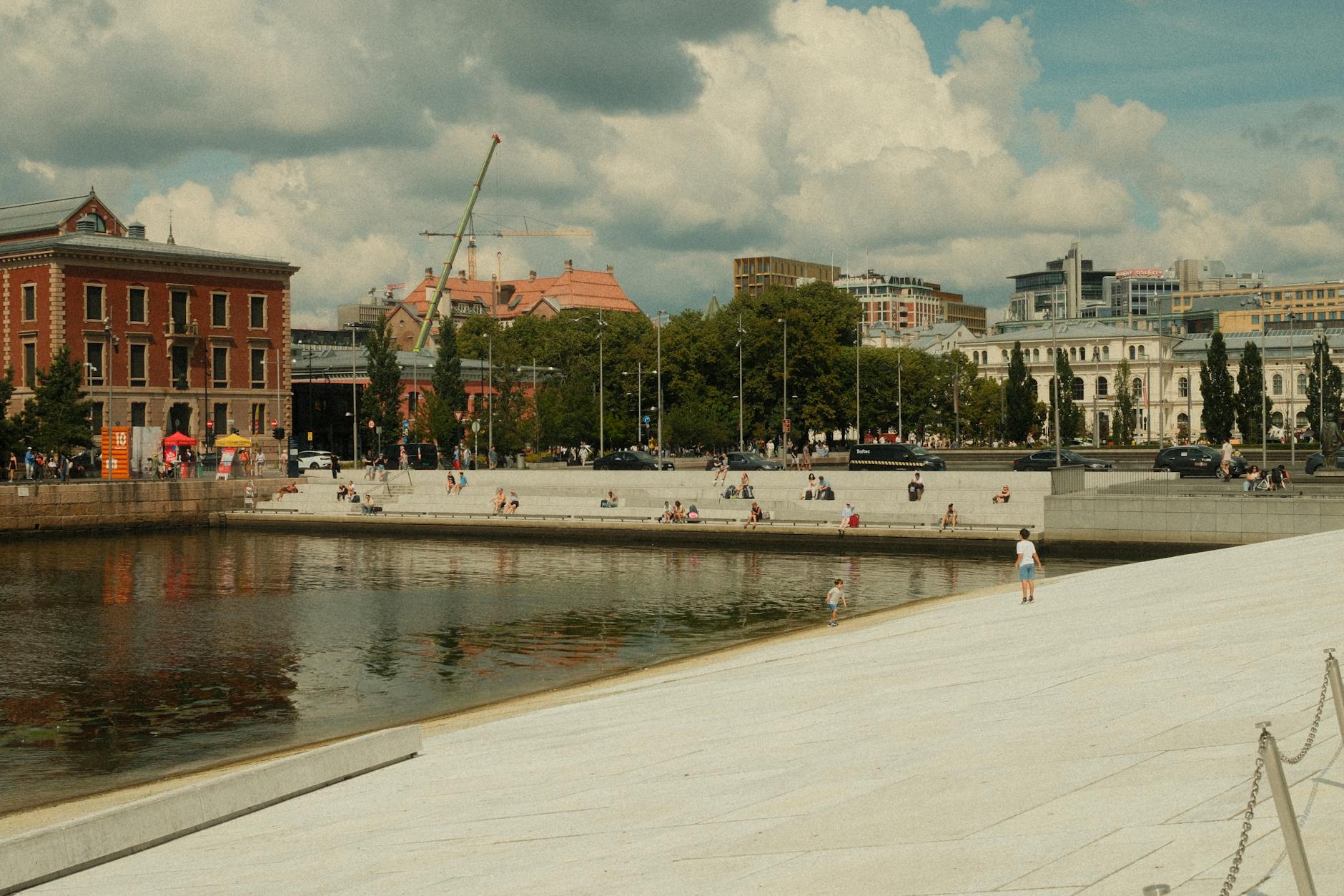 People enjoying a sunny waterfront plaza in Oslo