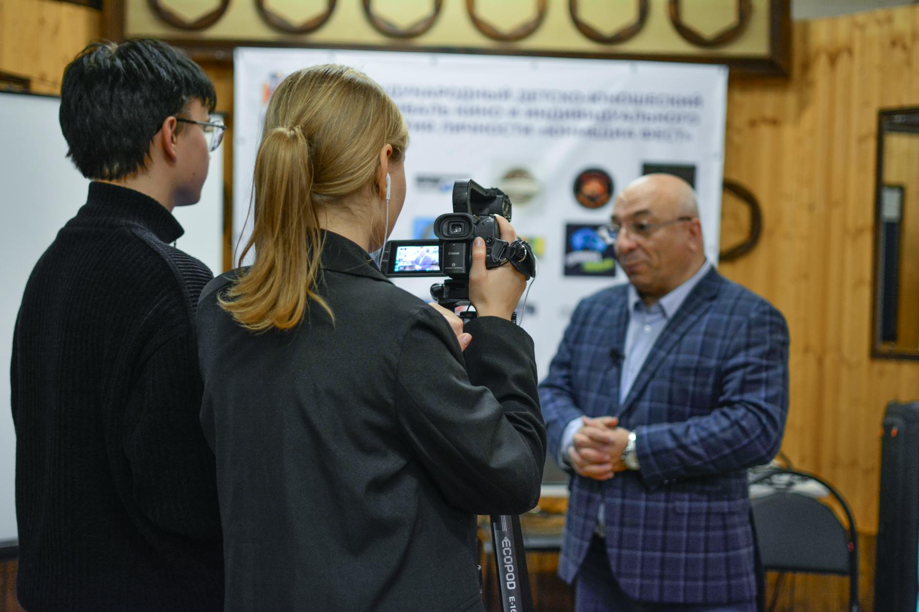 Journalist recording an interview indoors with a camcorder