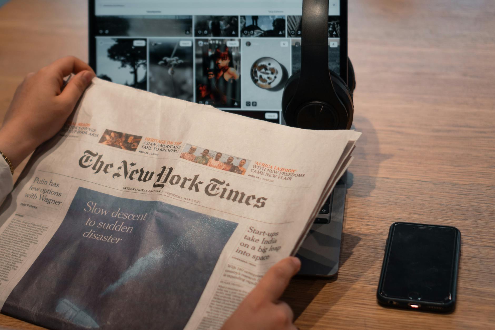 Newspaper, laptop, smartphone, and notes on a table