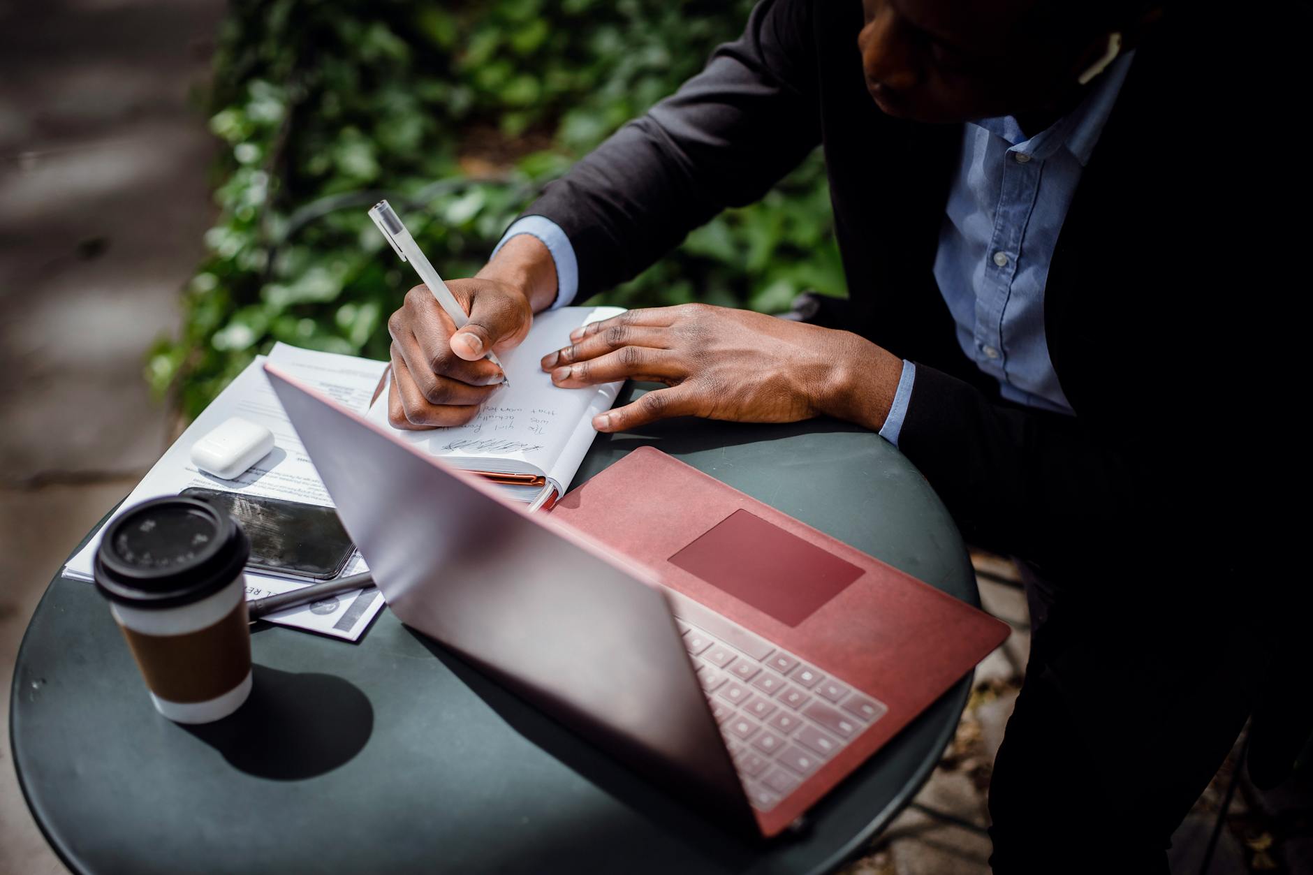 Journalist writing notes beside a laptop and coffee