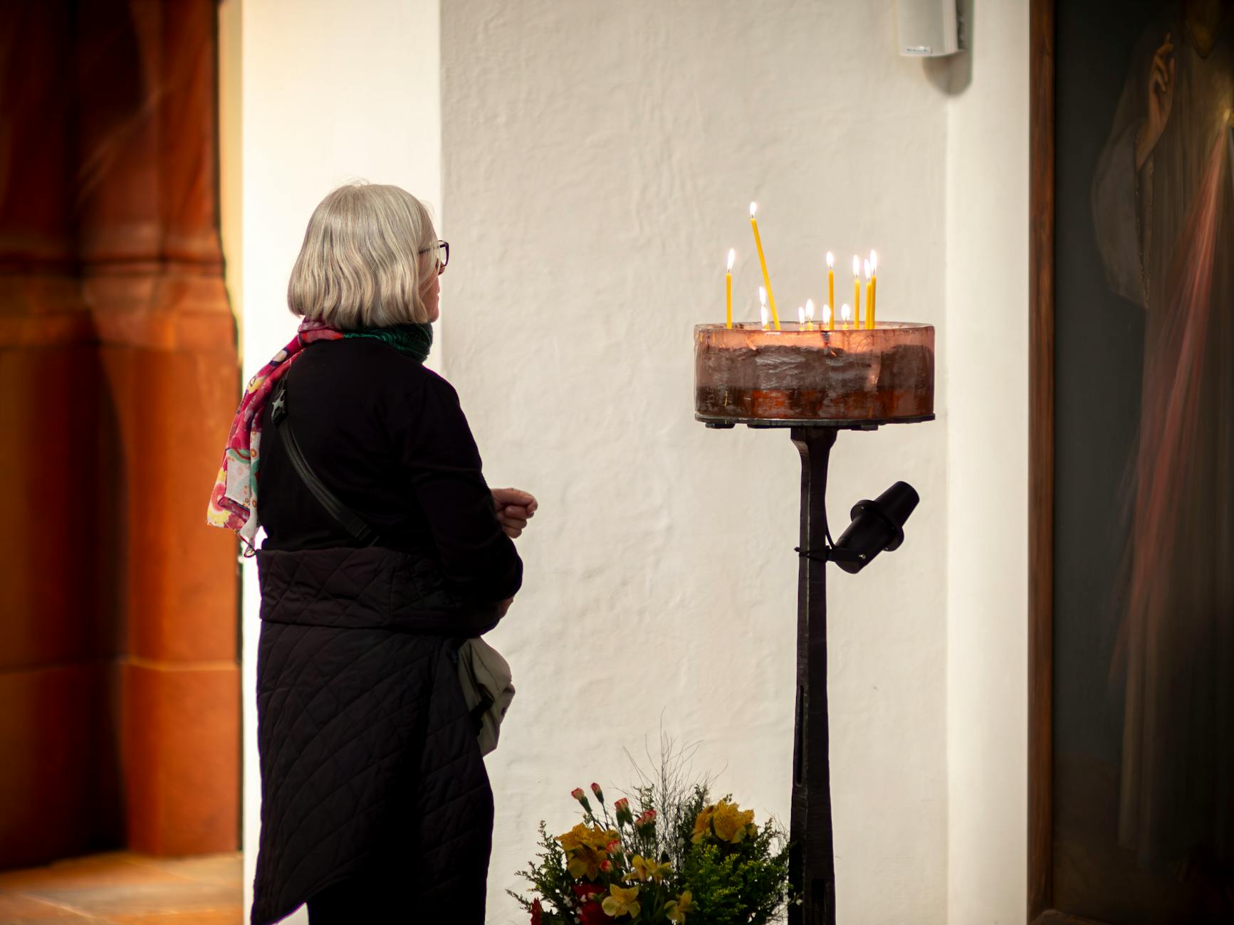 Person lighting candles in a quiet church interior