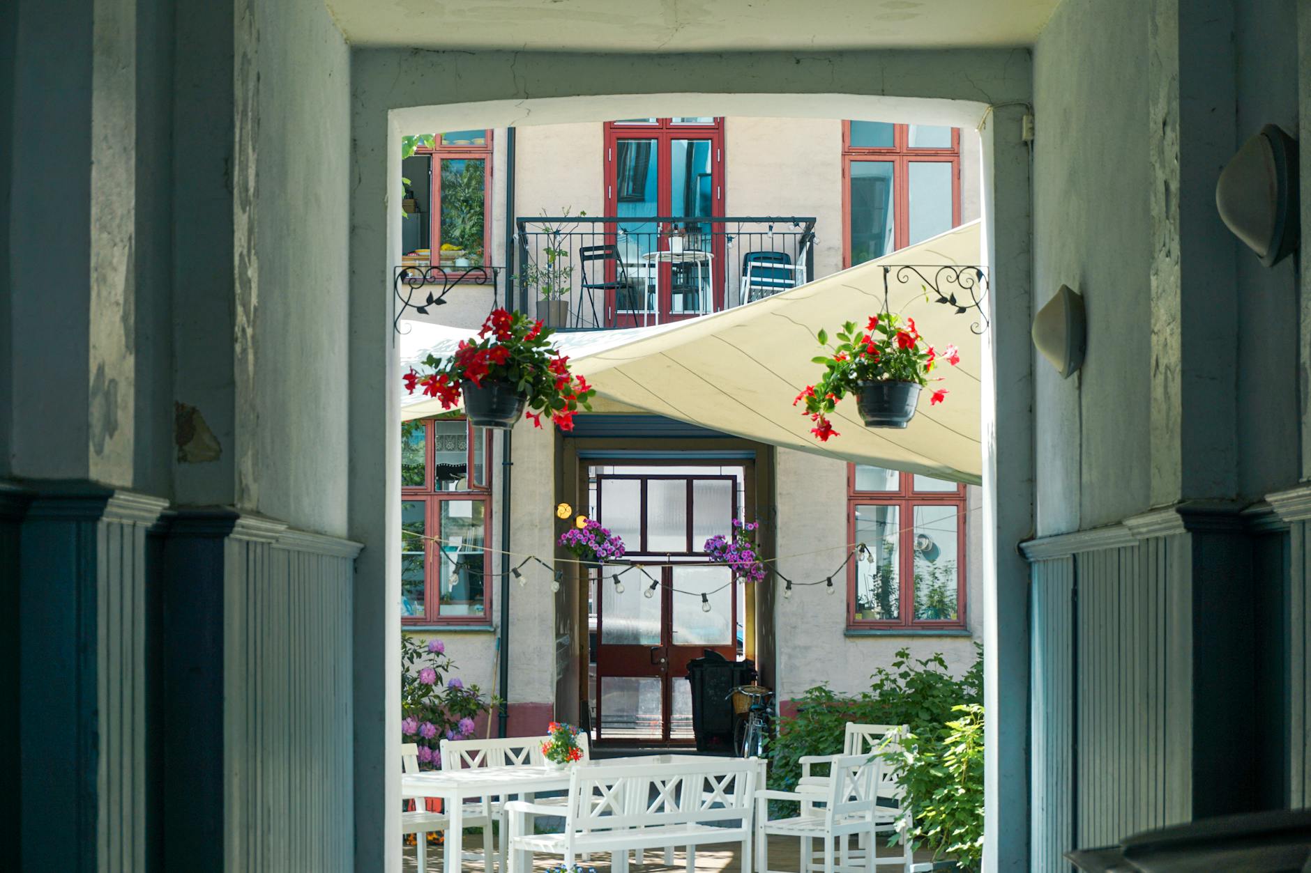 Outdoor cafe tables with hanging flowers in an Oslo courtyard
