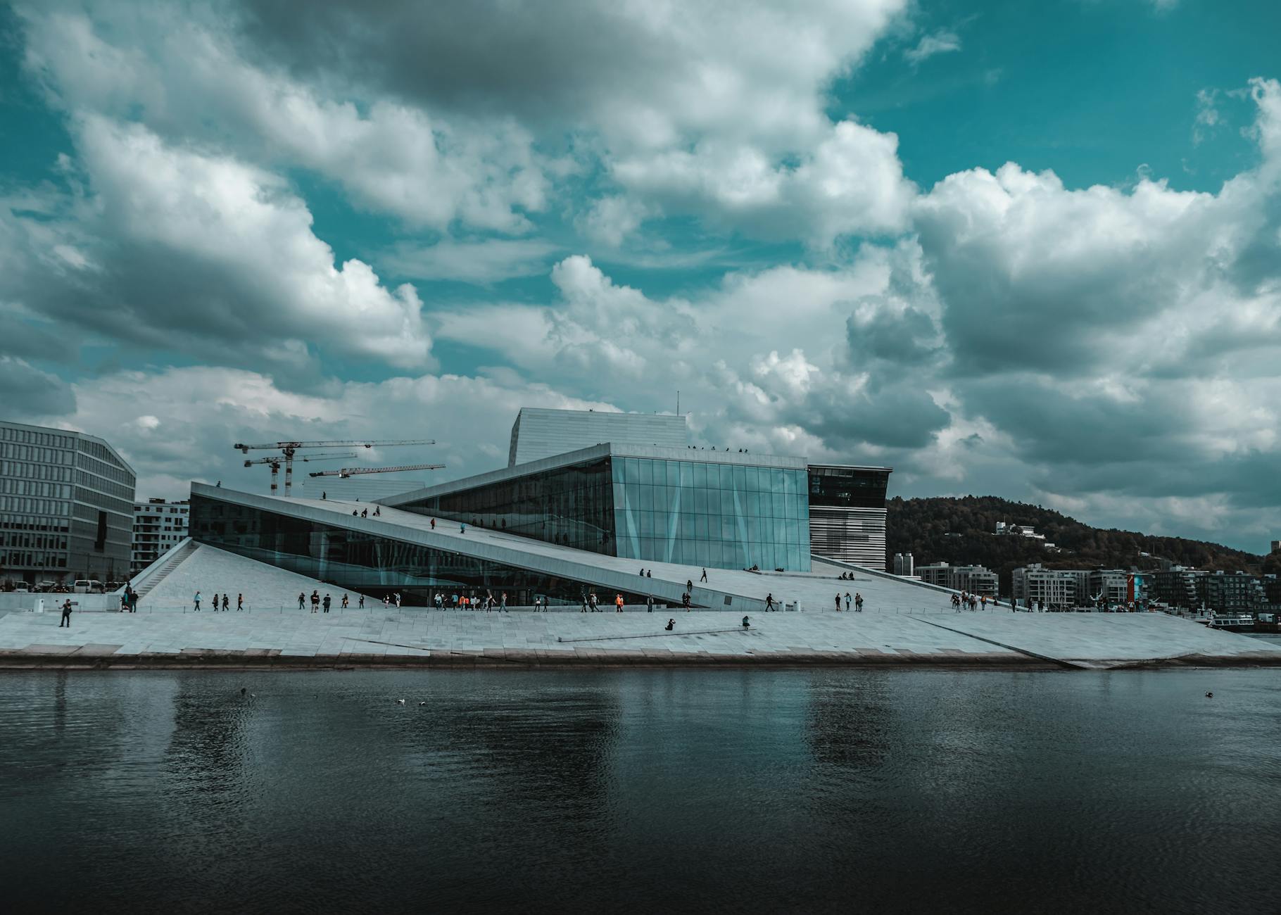 Oslo Opera House reflected on the waterfront under dramatic clouds
