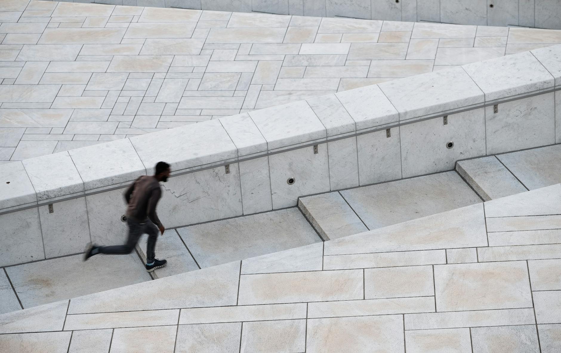 Traveler running up modern urban steps in Oslo