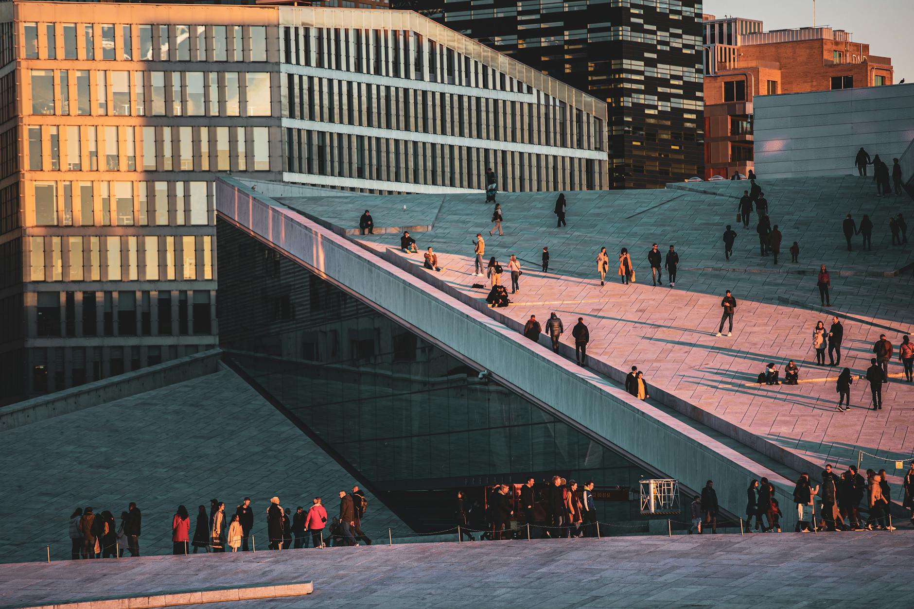 People walking on Oslo Opera House roof at sunset