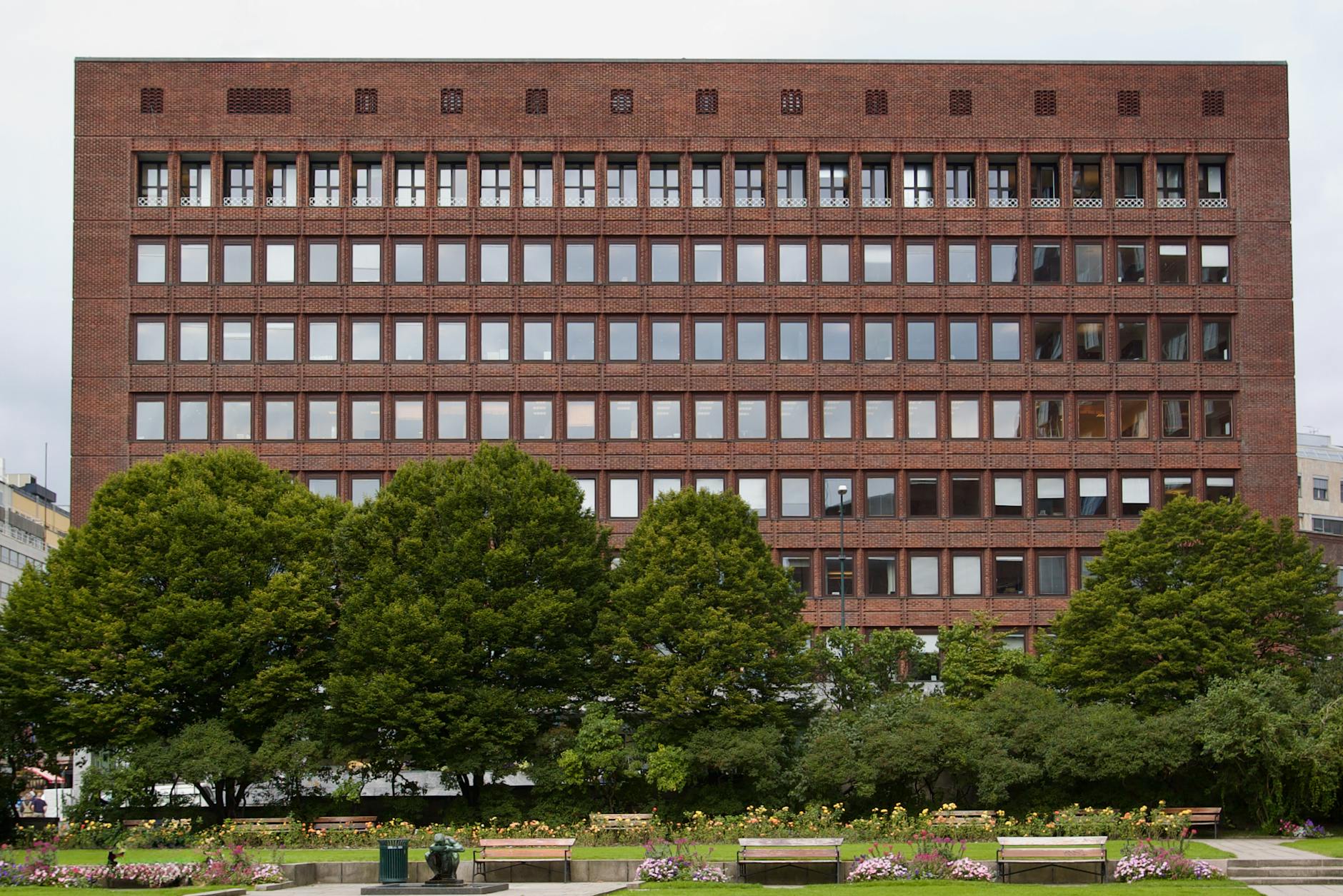 Red brick Oslo building with trees and landscaped greenery