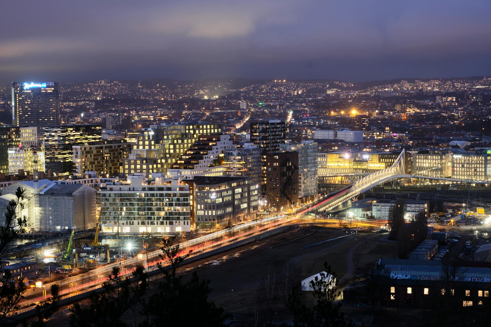 Oslo cityscape at dusk with illuminated buildings and bridge light trails
