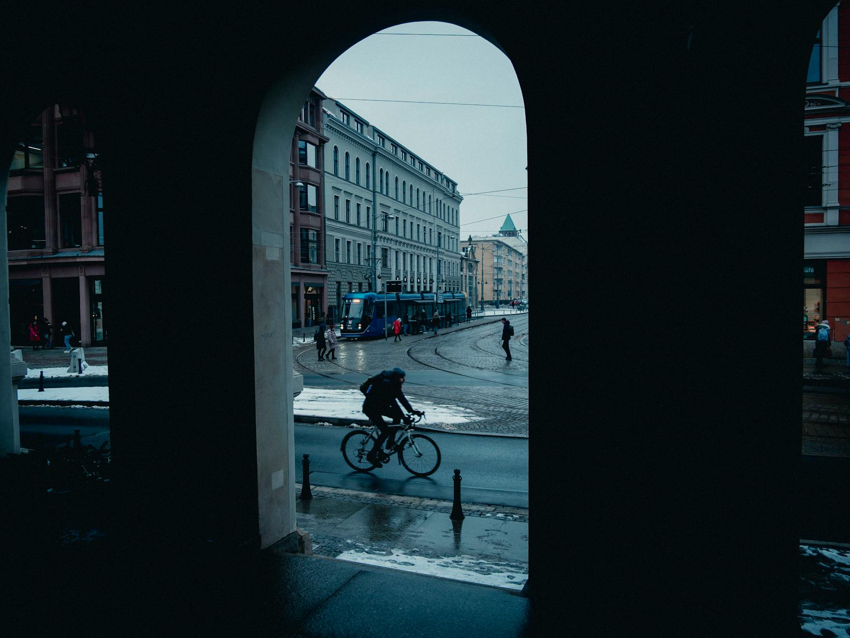Winter street scene with cyclist passing through an arch