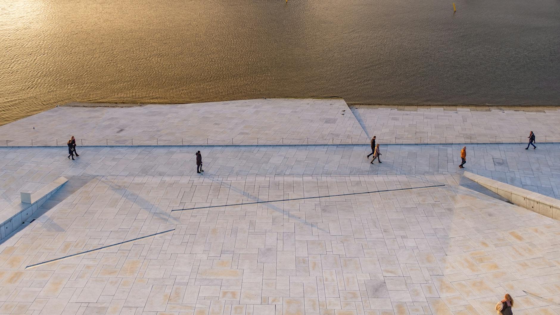 People walking along Oslo waterfront in evening light