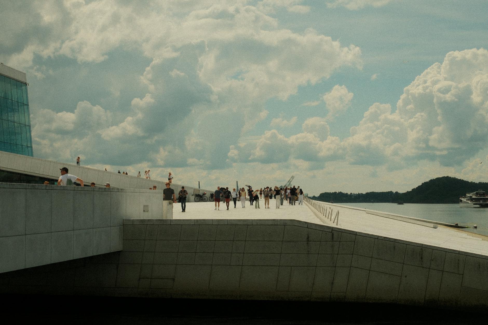 Visitors on Oslo Opera House rooftop under dramatic clouds
