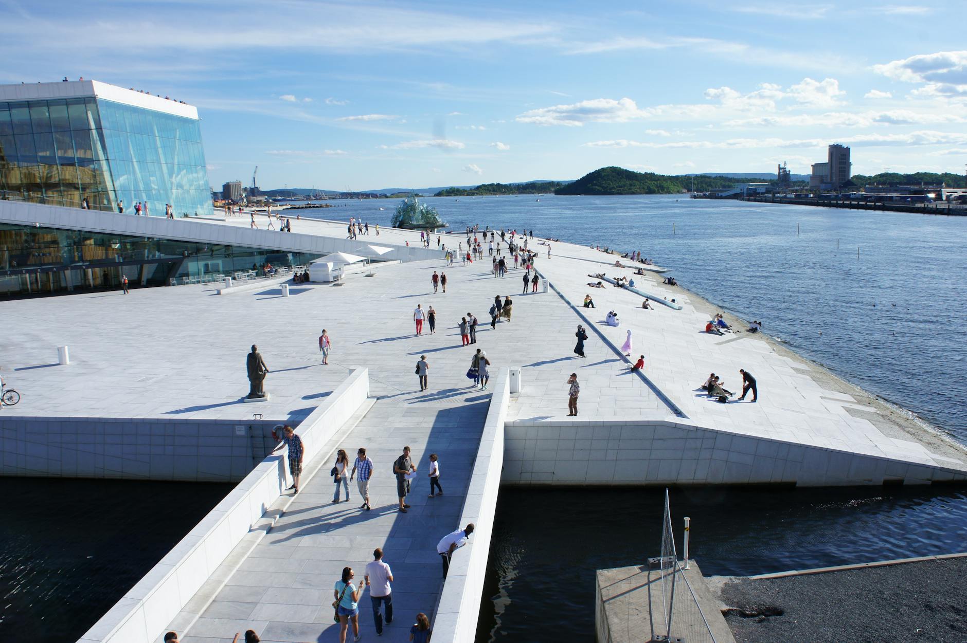 Travelers walking along a modern Oslo waterfront embankment