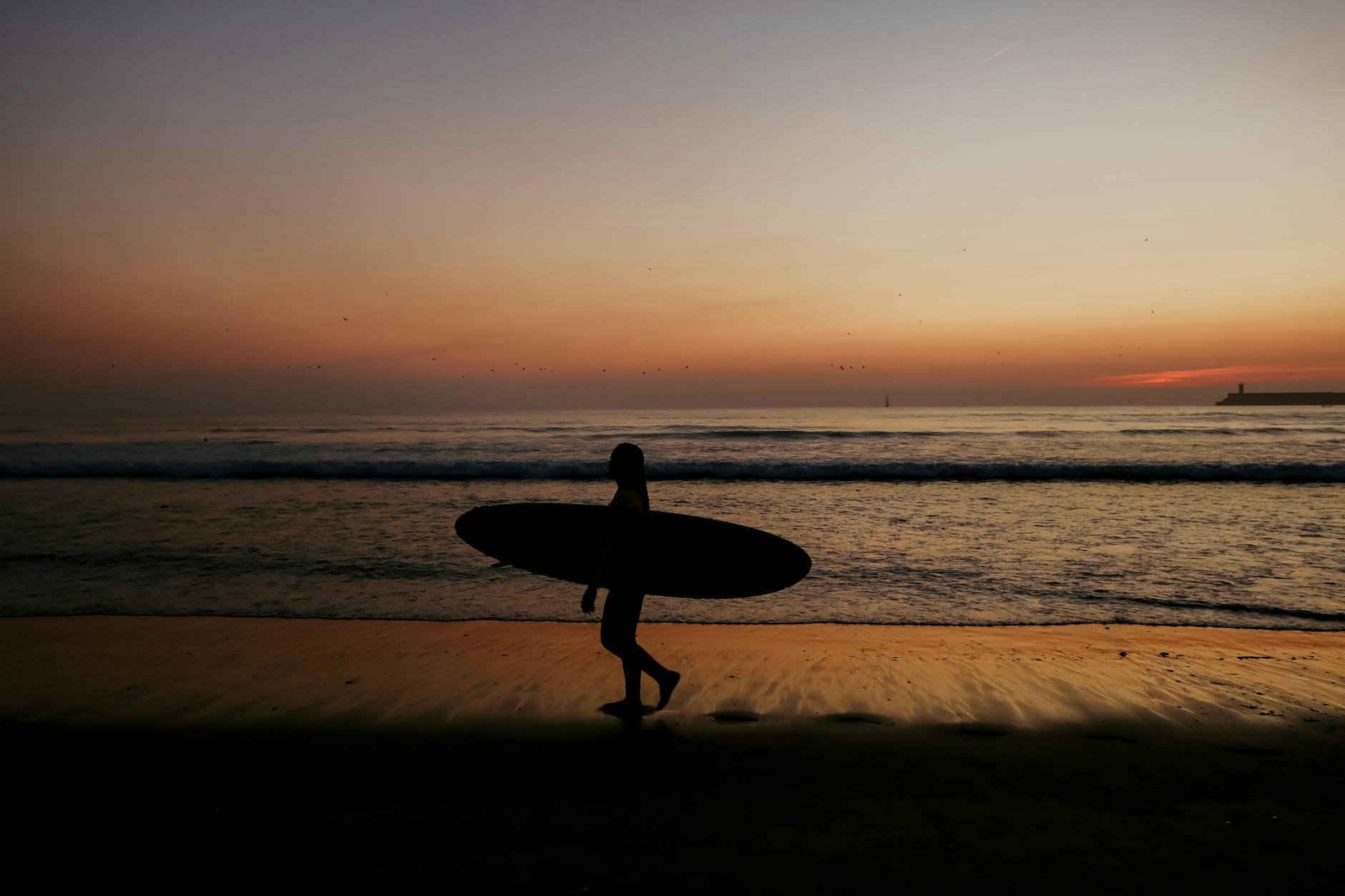 Surfer walking along Matosinhos Beach at sunset