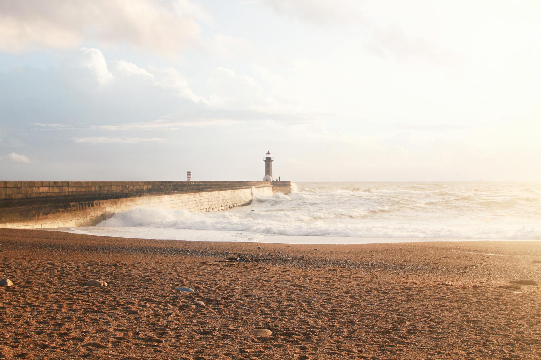 Porto lighthouse with waves crashing at sunset