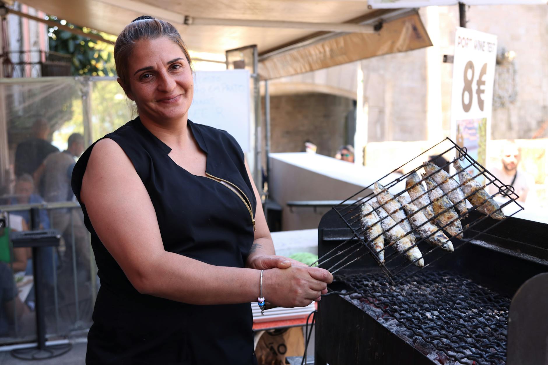 Chef grilling fish at an outdoor food stall in Porto