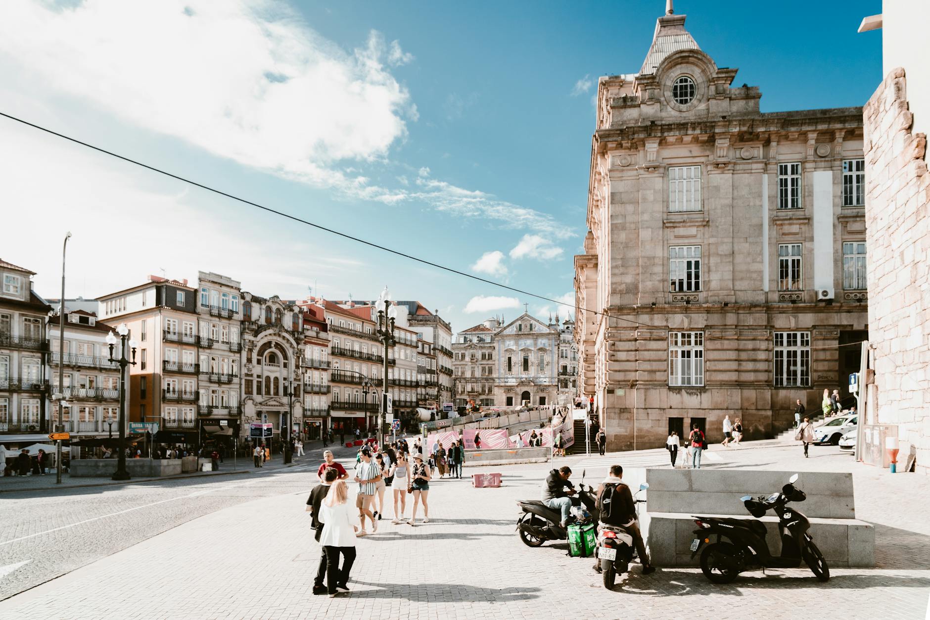 Busy street near Sao Bento Station in Porto with people and scooters