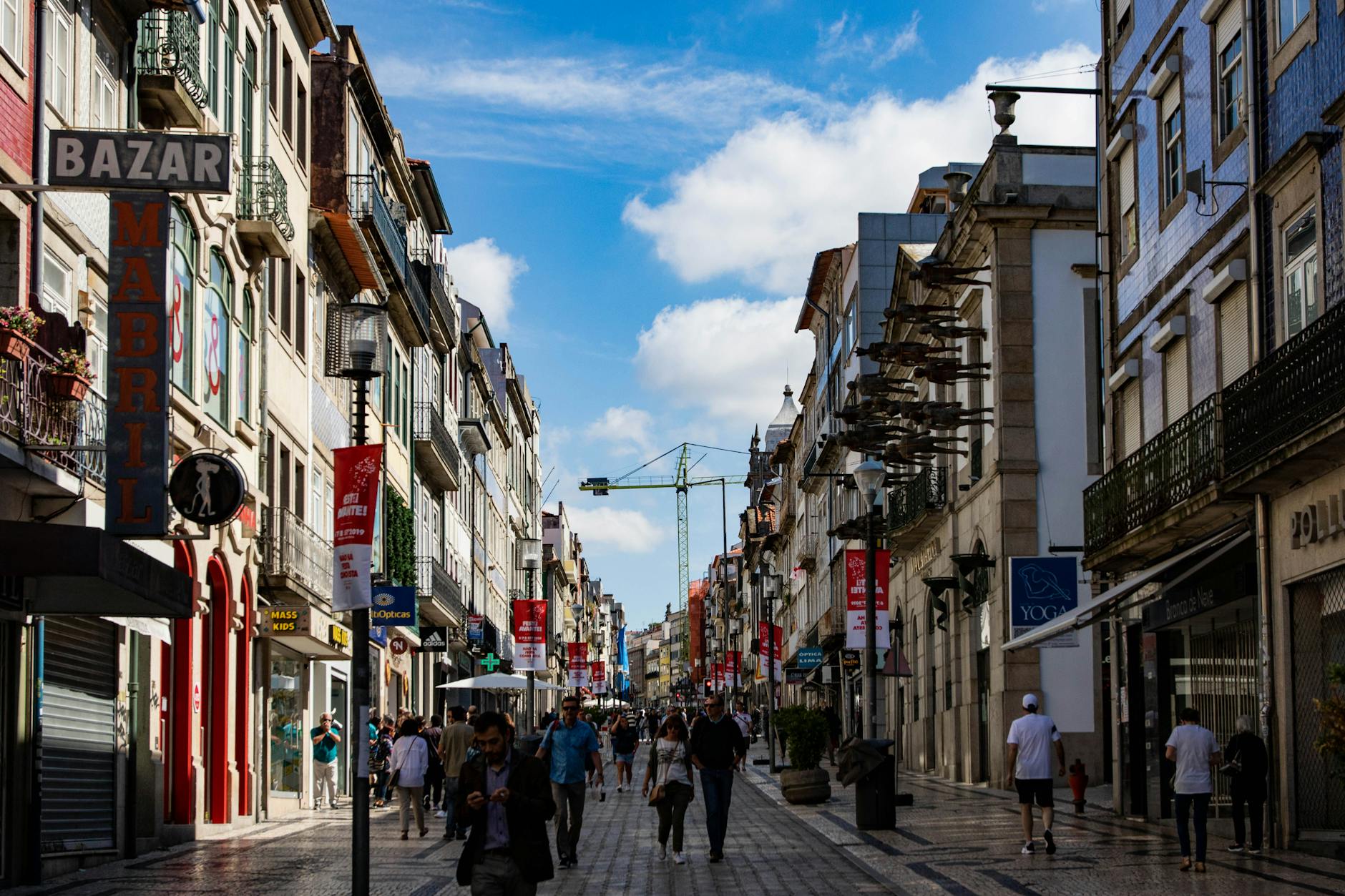 Lively Porto street with shops and pedestrians under a blue sky