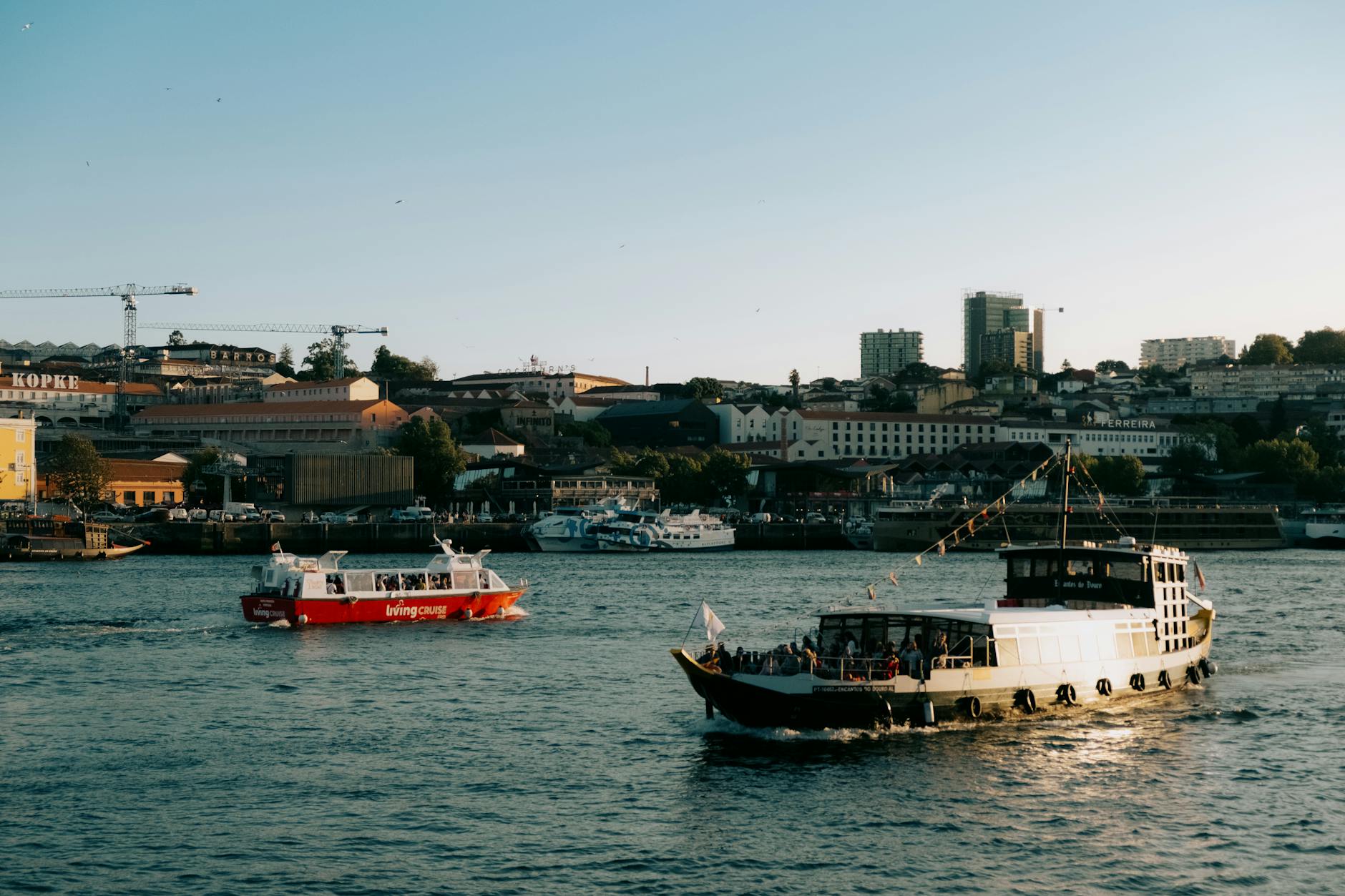 Boats cruising along Porto waterfront under a clear sky