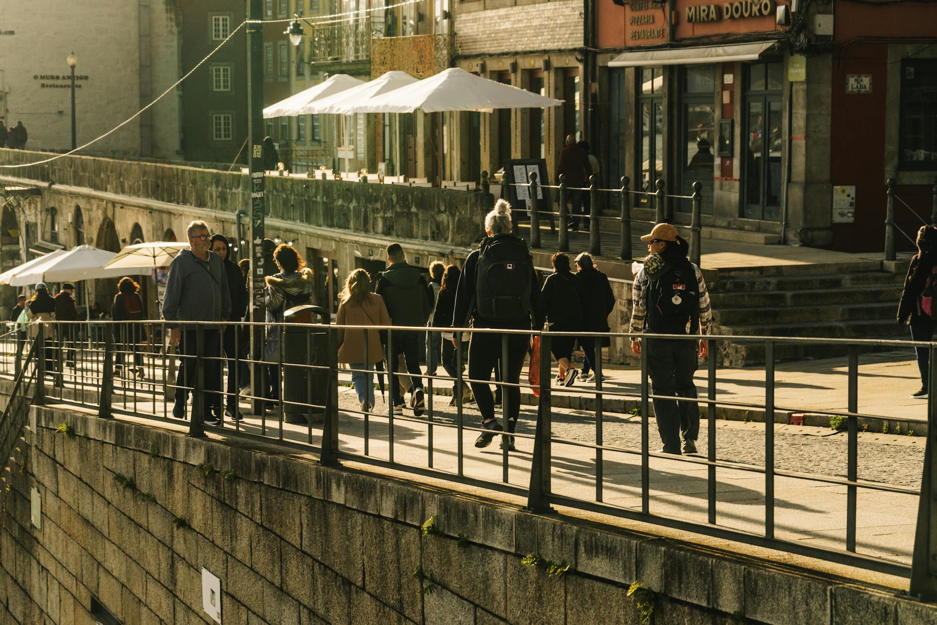 People walking along a busy Porto street in warm sunlight
