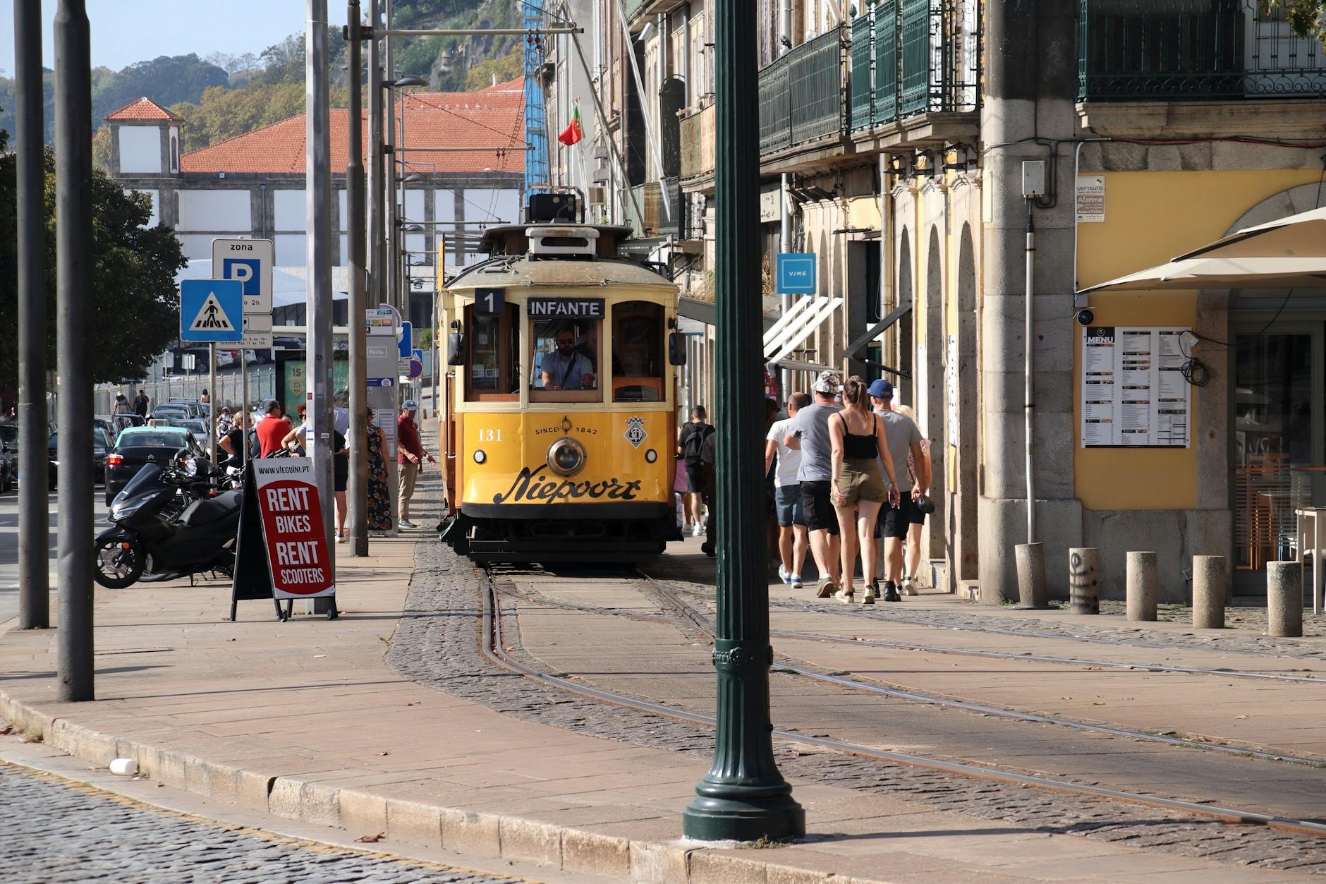 Yellow tram on a sunny Porto cobblestone street