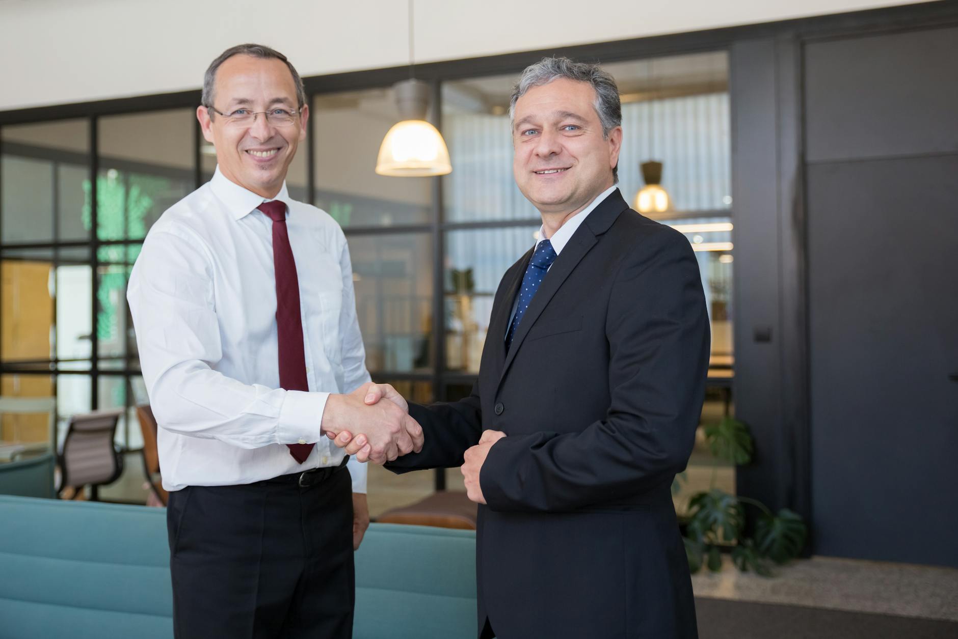 Businessmen shaking hands across a desk in an office