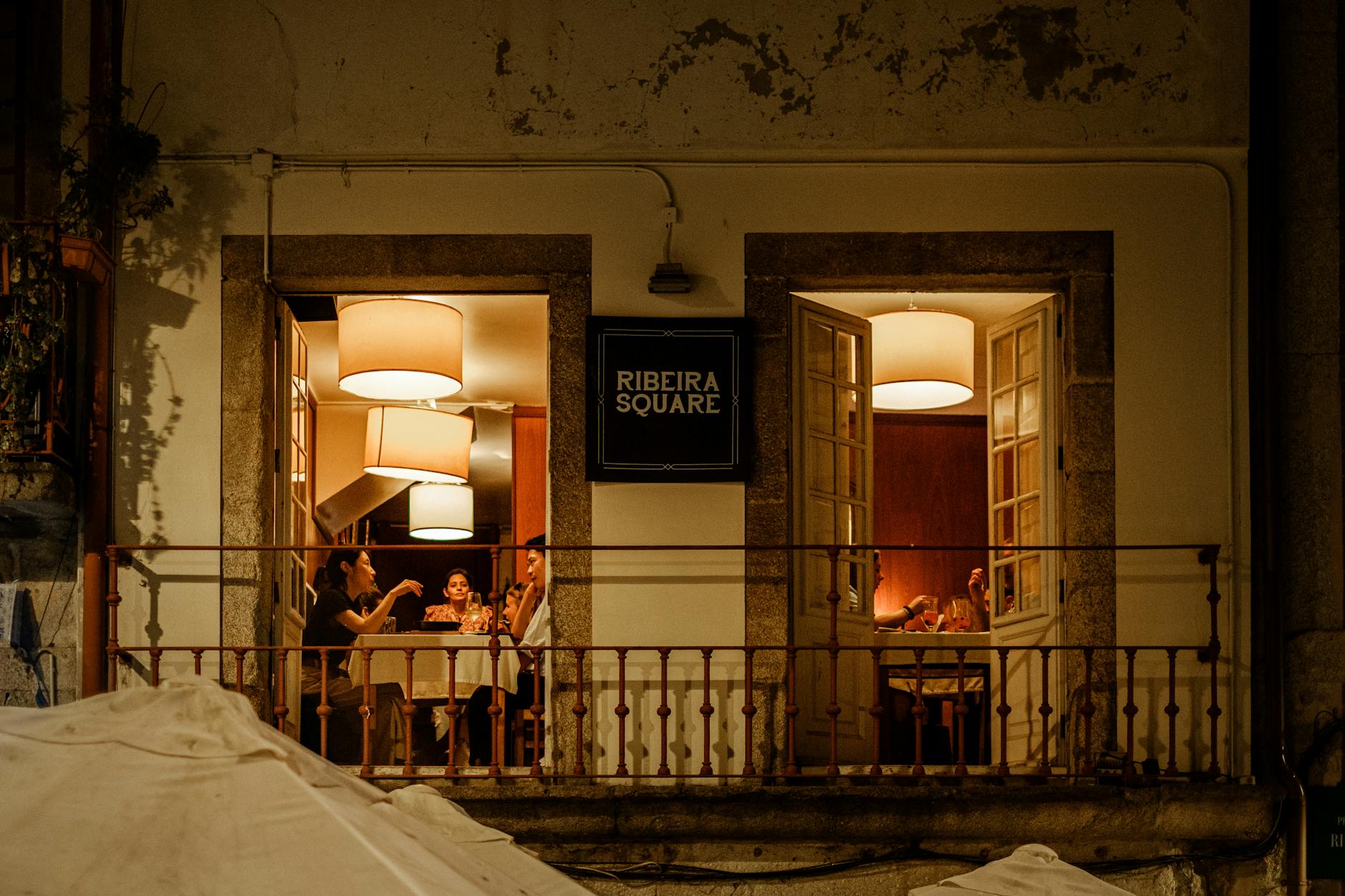 People dining in Ribeira Square in Porto with warm evening ambiance