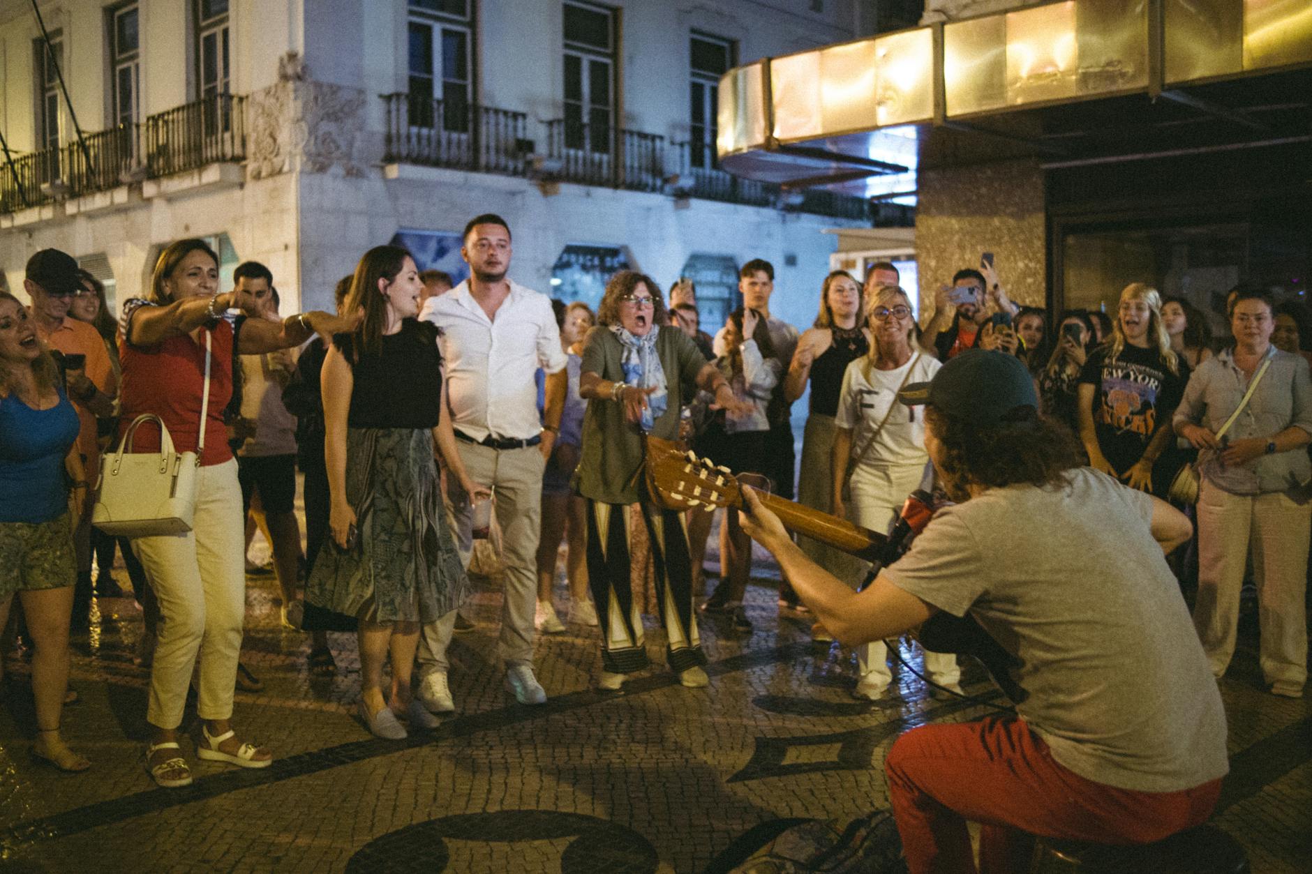 Street musician playing guitar for a lively night crowd
