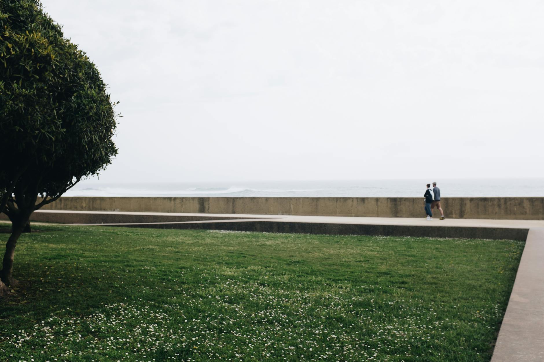 Two people walking by the sea in a Porto park