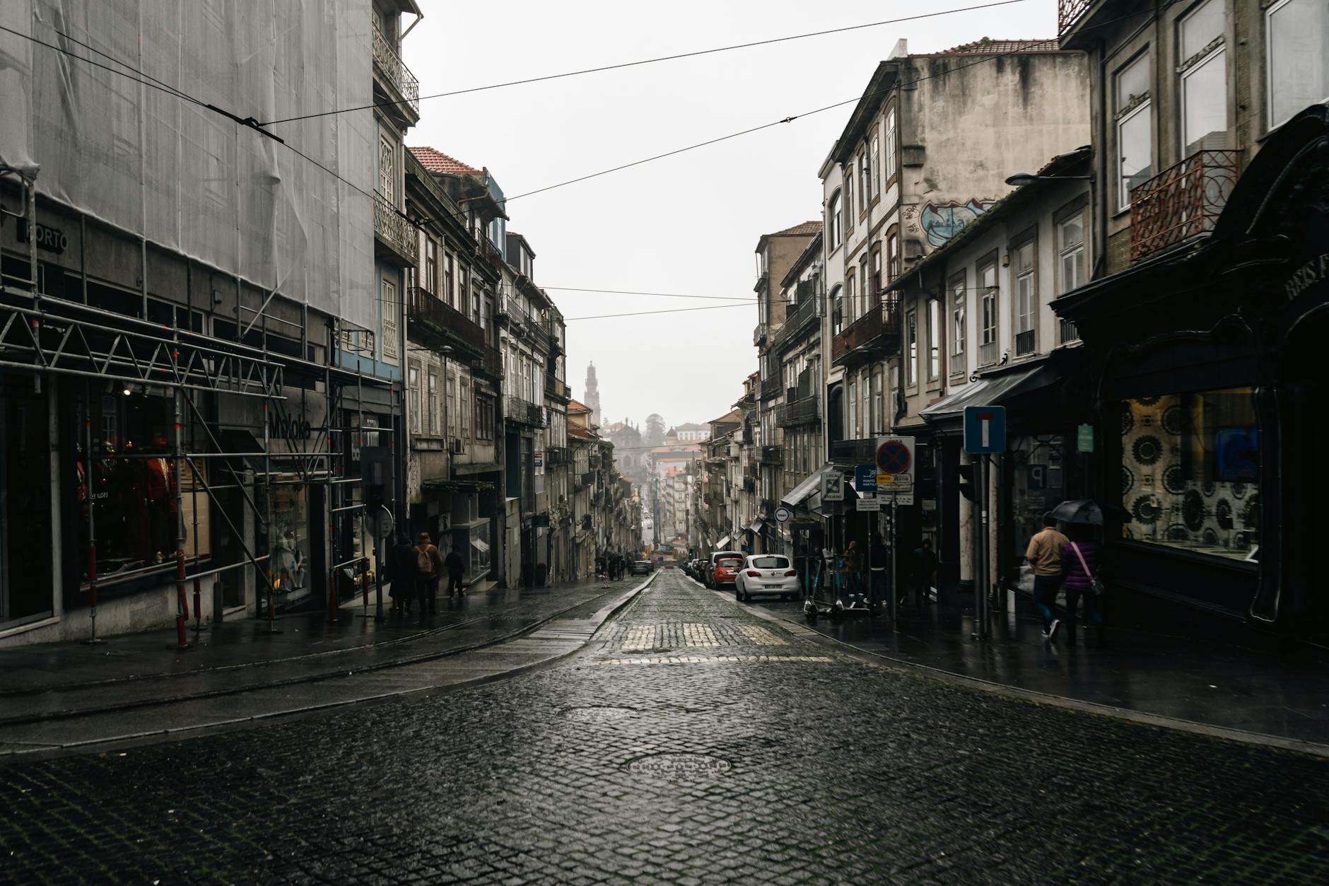 Rainy cobblestone street in Porto with pedestrians