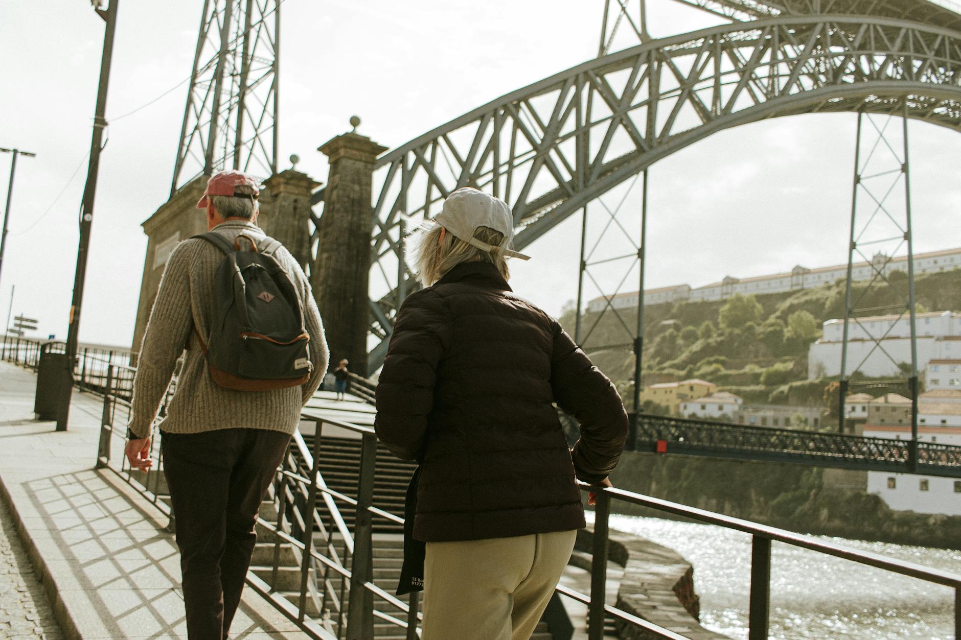 Two tourists walking under the Dom Luis I Bridge in Porto