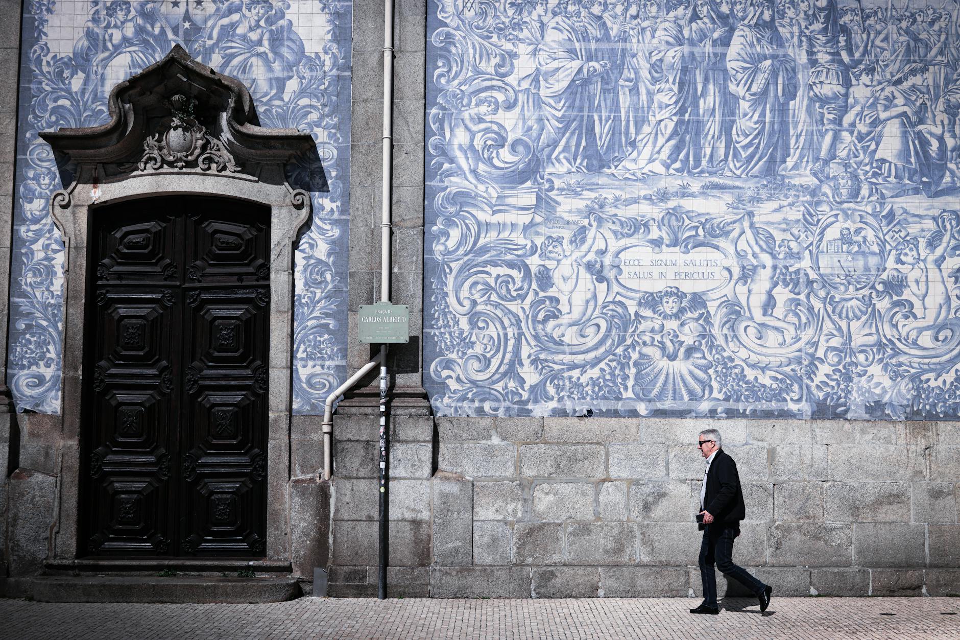 Man walking beside a traditional azulejo wall in Porto