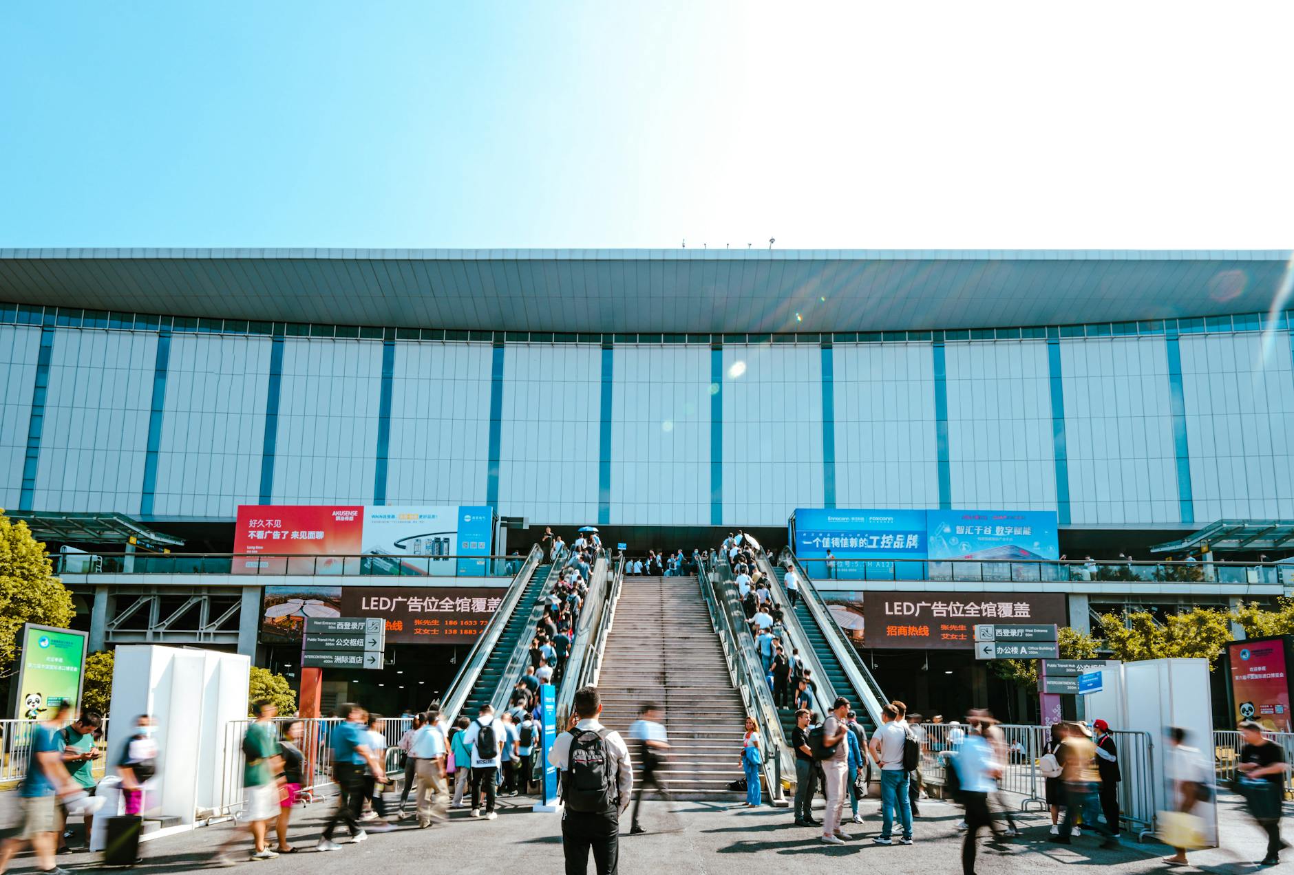 People entering an exhibition center by outdoor escalator