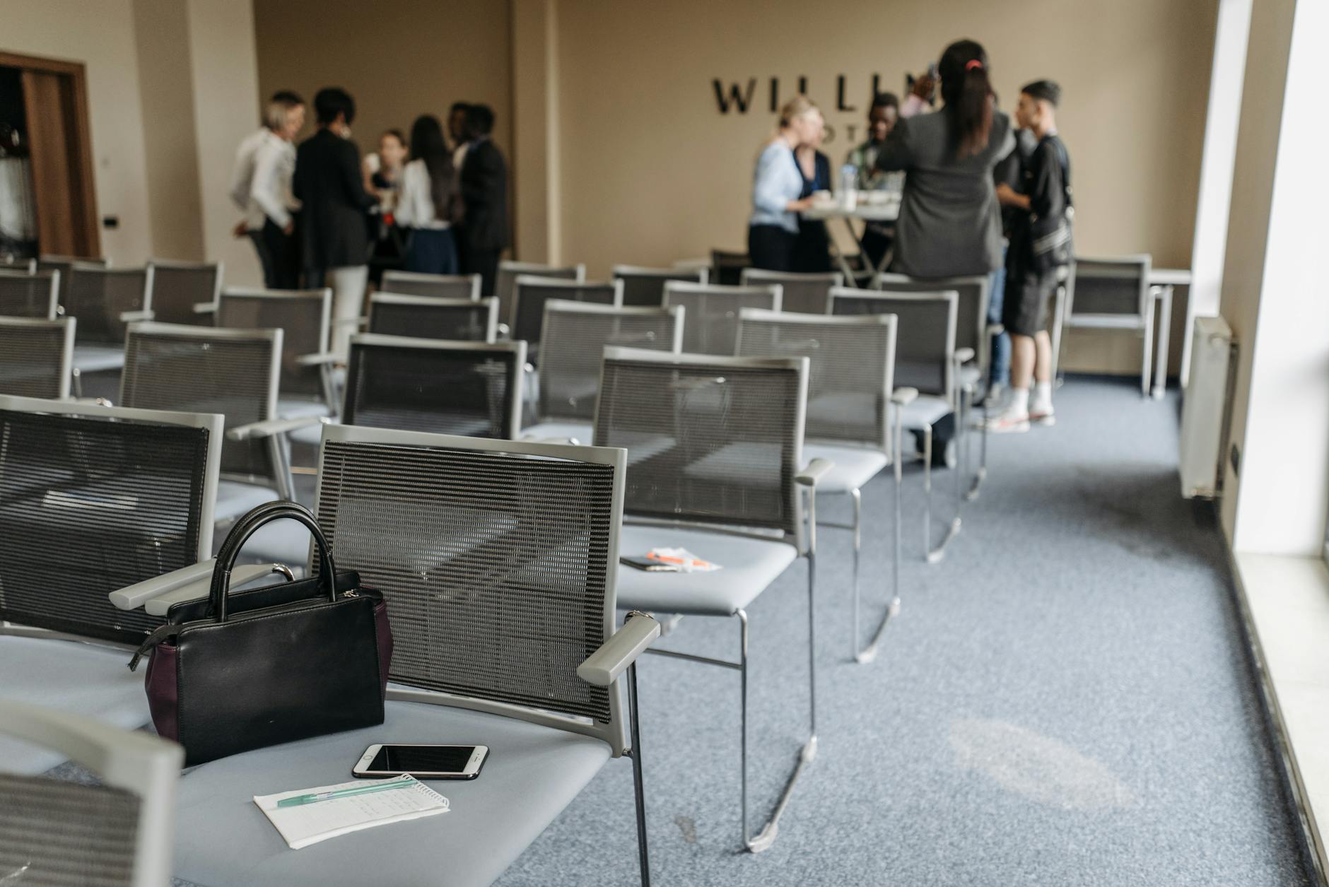 Conference room with chairs and people gathered at the back