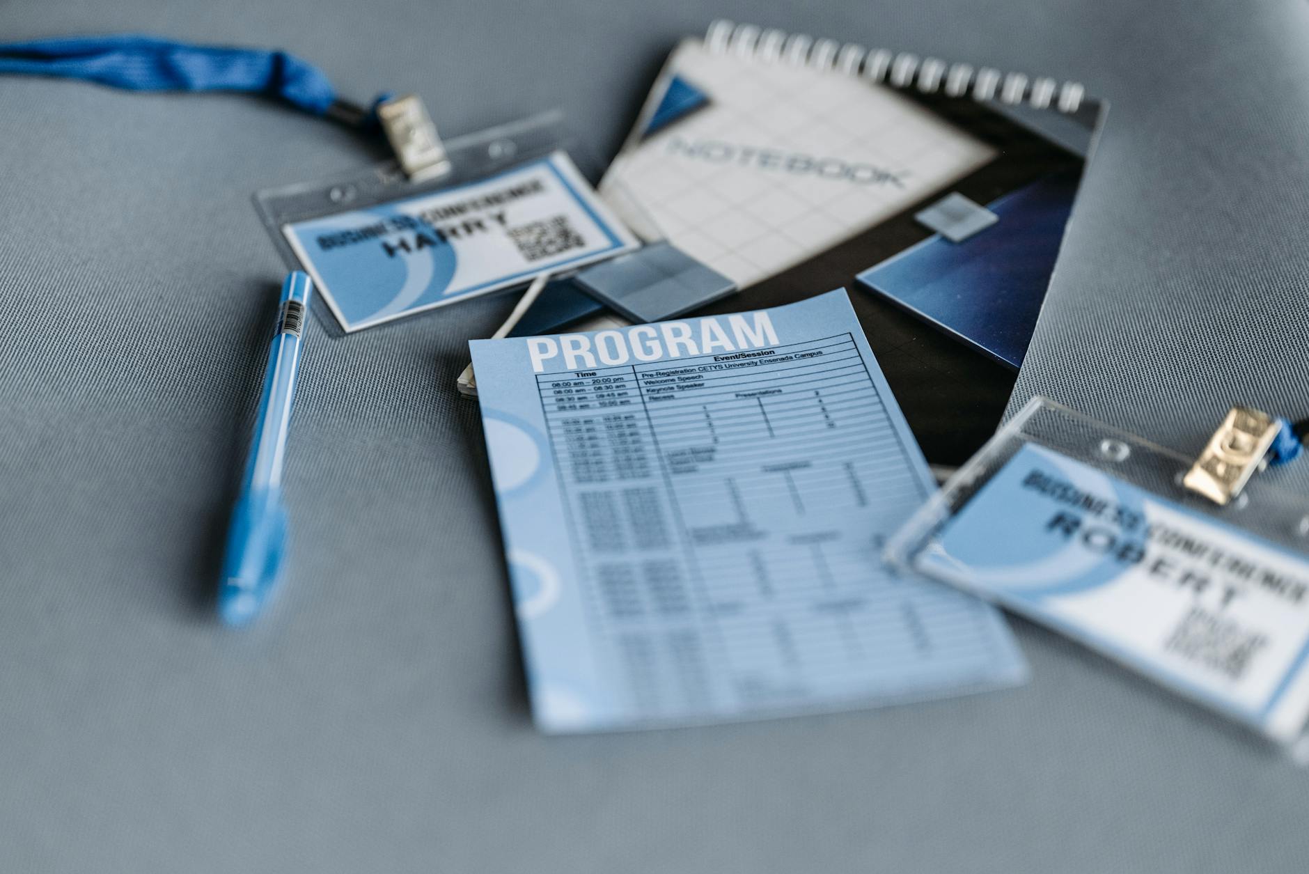 Conference badges, program, and pen laid out on a table