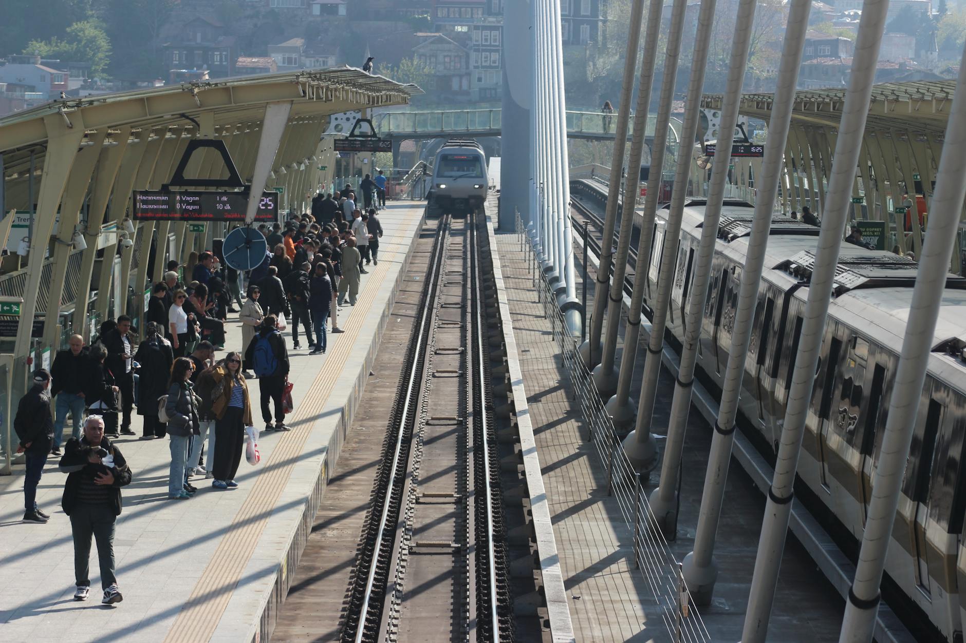 Crowds waiting on a train station platform as trains arrive