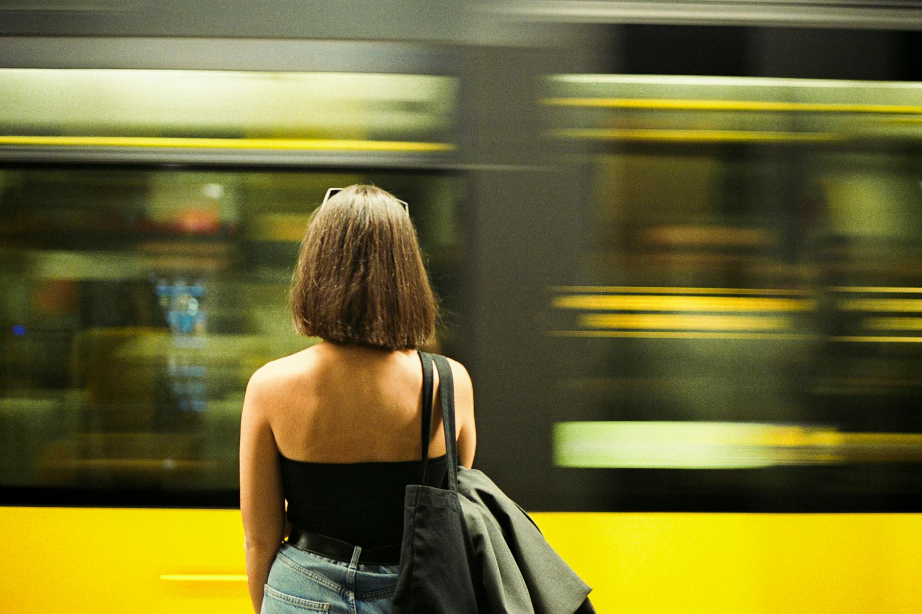 Woman at a Porto metro station with a train speeding by